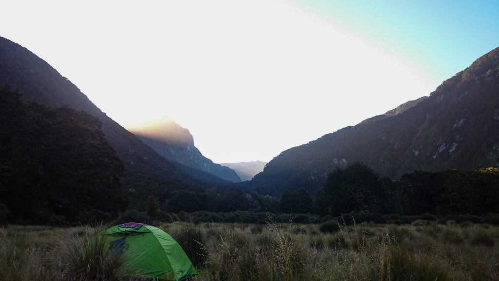 Wanderung Kepler Track - Great Walk, nach Wanderweg entlang Bergkamm im rauen Gelände, alpin oberhalb Baumgrenze, herrliche Aussicht auf umliegende Berge im flacheren Tal, herrlicher Sommertag in Neuseeland Südinsel, Fiordland National Park, Sonnenuntergang, Wandertag beim Kepler Track, Campingplatz Iris Burn am Ende des zweiten Wandertages