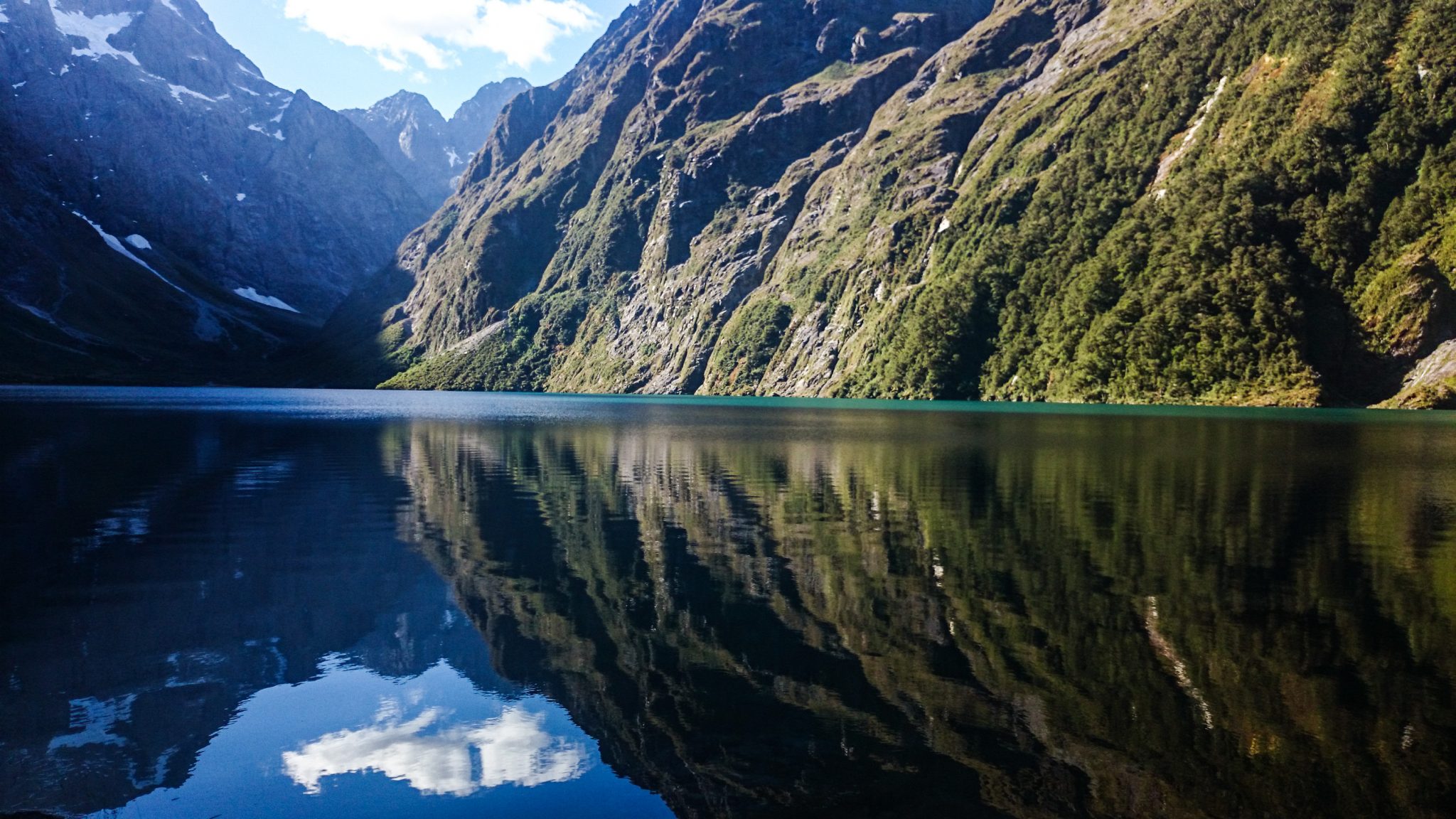 Lake Marian Track wandern, bei Marian Falls im Fiordland National Park Südinsel Neuseelands, Wanderung zum See Marian, Lake Marian, Tal, hanging valley, schneebedeckte Gipfel in der Ferne, Berge spiegeln sich im klaren Wasser, schönes Licht, Sonne, Steine