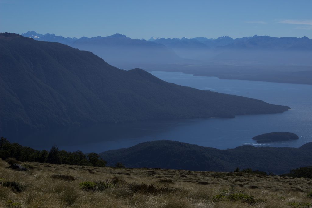 Wanderung Kepler Track - Great Walk, Wanderweg entlang Bergkamm im rauen Gelände, alpin oberhalb Baumgrenze, herrliche Aussicht, dunkelblauer See, herrlicher Sommertag in Neuseeland Südinsel, Fiordland National Park, Wandertag beim Kepler Track