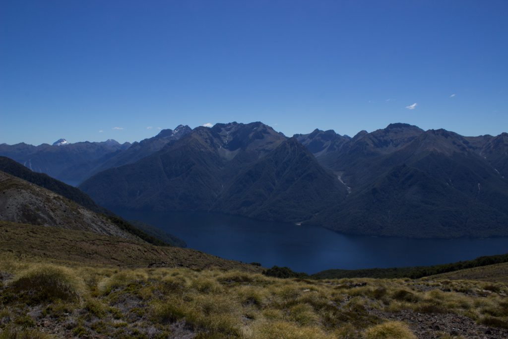 Wanderung Kepler Track - Great Walk, Wanderweg entlang Bergkamm im rauen Gelände, alpin oberhalb Baumgrenze, herrliche Aussicht, dunkelblauer See, herrlicher Sommertag in Neuseeland Südinsel, Fiordland National Park, Wandertag beim Kepler Track