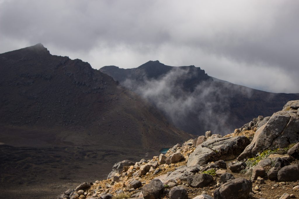 Tongariro Alpine Crossing Wanderung, Vulkanlandschaft, lebensfeindliche Landschaft, in Wolken gehüllte Berge, Geröll und Steine, Berggipfel in der Ferne, tolle Wanderung auf Nordinsel Neuseelands