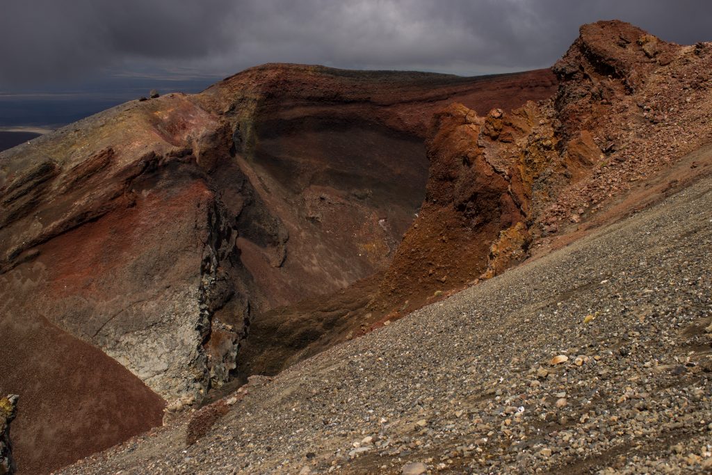 Tongariro Alpine Crossing Wanderung, Nordinsel Neuseeland, Vulkanlandschaft, lebensfeindliche Landschaft, in Wolken gehüllte Berge, Geröll und Steine, rote Vulkanasche, Red Crater