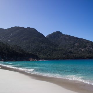 Wineglass Bay, Bucht im traumhaften Freycinet Nationalpark in Tasmanien, saftig grüner Wald, Berge, Strand mit schneeweißem Zuckersand und kristallklarem Wasser, Traumstrand