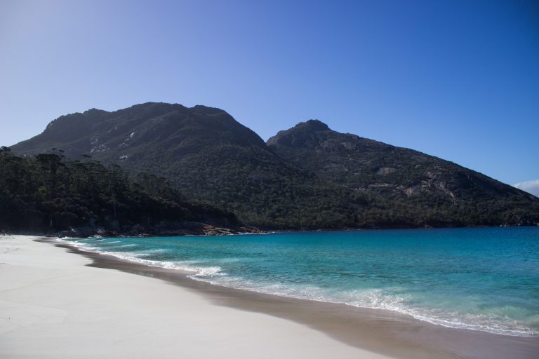Wineglass Bay, Bucht im traumhaften Freycinet Nationalpark in Tasmanien, saftig grüner Wald, Berge, Strand mit schneeweißem Zuckersand und kristallklarem Wasser, Traumstrand