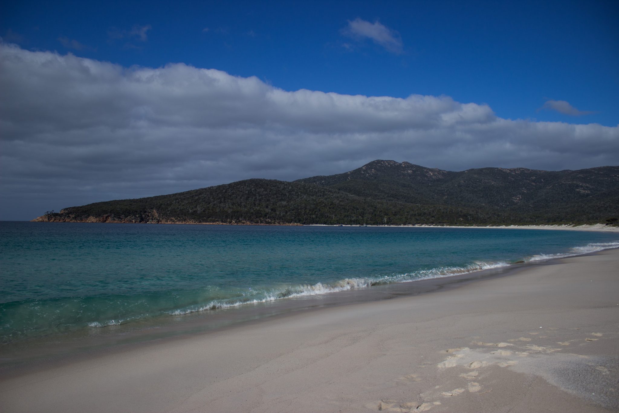 Wineglass Bay, Bucht im traumhaften Freycinet Nationalpark in Tasmanien, saftig grüner Wald, Berge, Strand mit schneeweißem Zuckersand und kristallklarem Wasser, Traumstrand