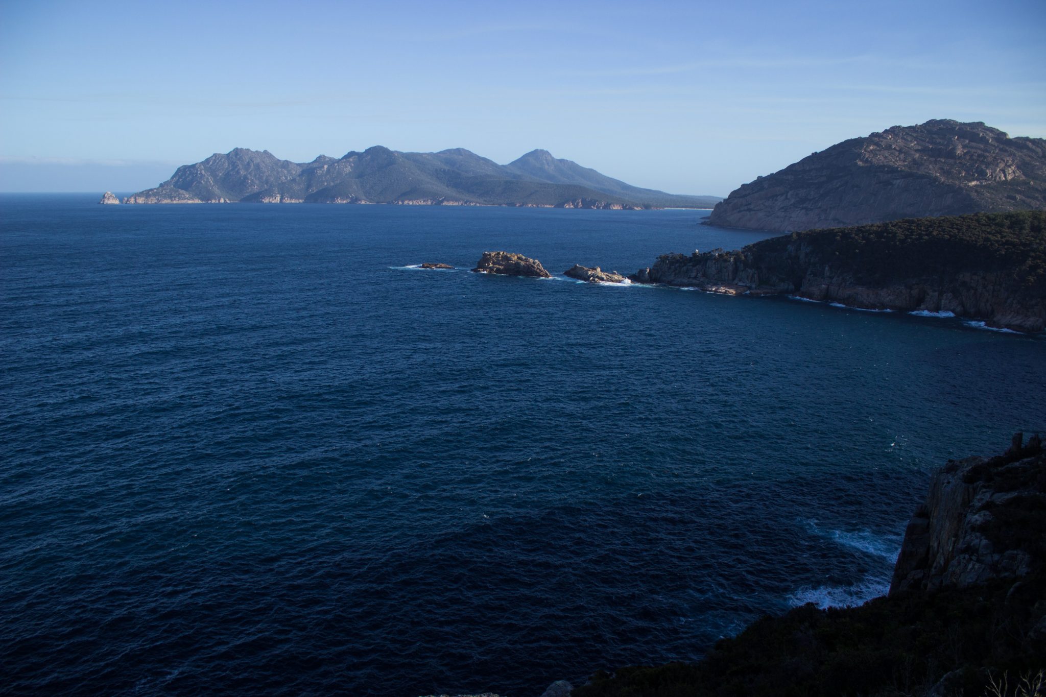 im traumhaften Freycinet Nationalpark in Tasmanien, saftig grüner Wald, Berge in der Ferne, wunderschönes Meer Ozean, Wellen