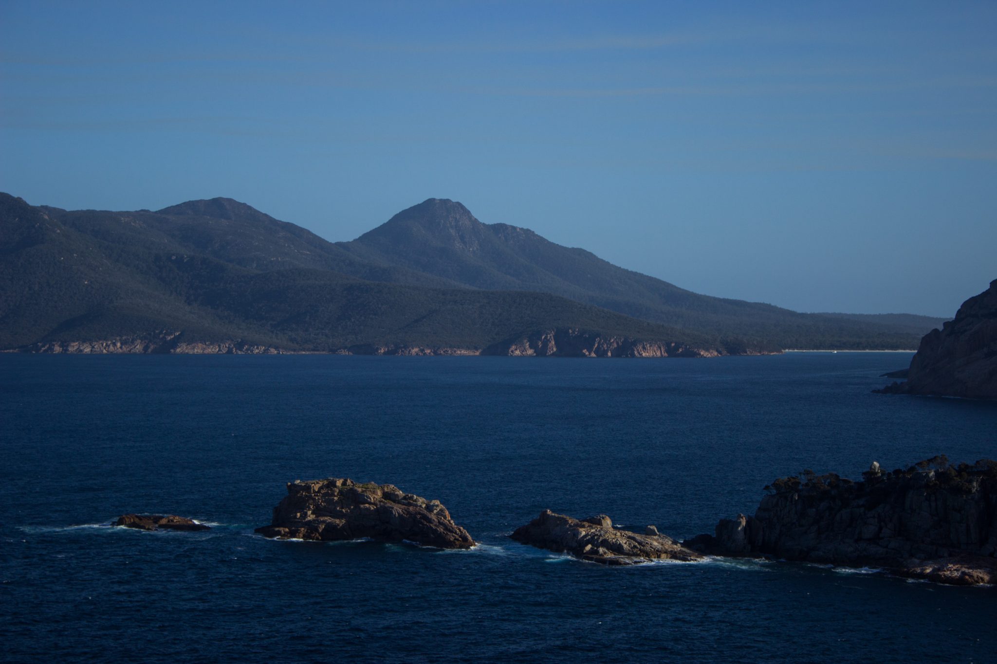 im traumhaften Freycinet Nationalpark in Tasmanien, saftig grüner Wald, Berge in der Ferne, wunderschönes Meer Ozean, Wellen