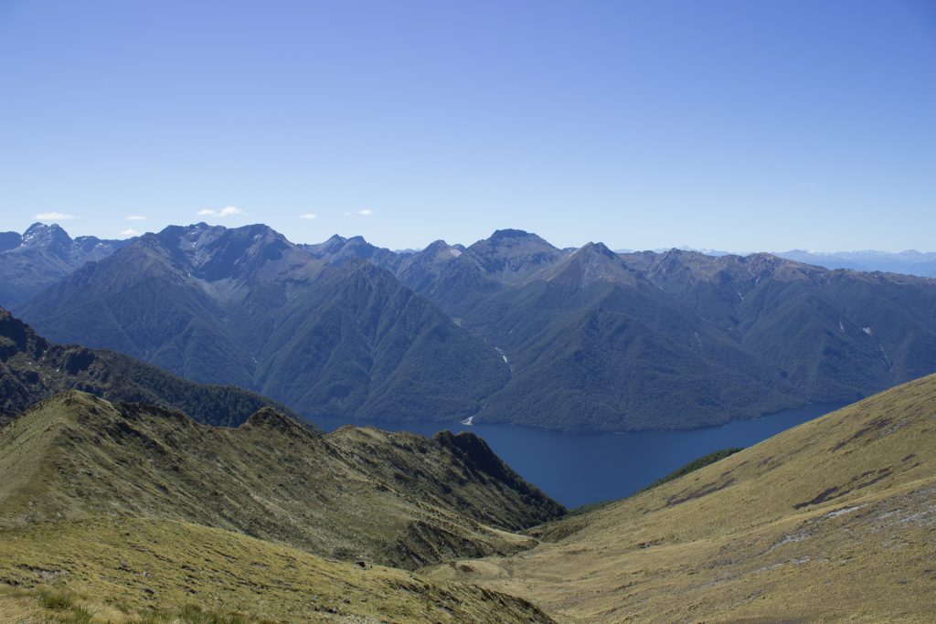 Wanderung Kepler Track - Great Walk, Wanderweg entlang Bergkamm im rauen Gelände, alpin oberhalb Baumgrenze, herrliche Aussicht, dunkelblauer See, herrlicher Sommertag in Neuseeland Südinsel, Fiordland National Park, Wandertag beim Kepler Track