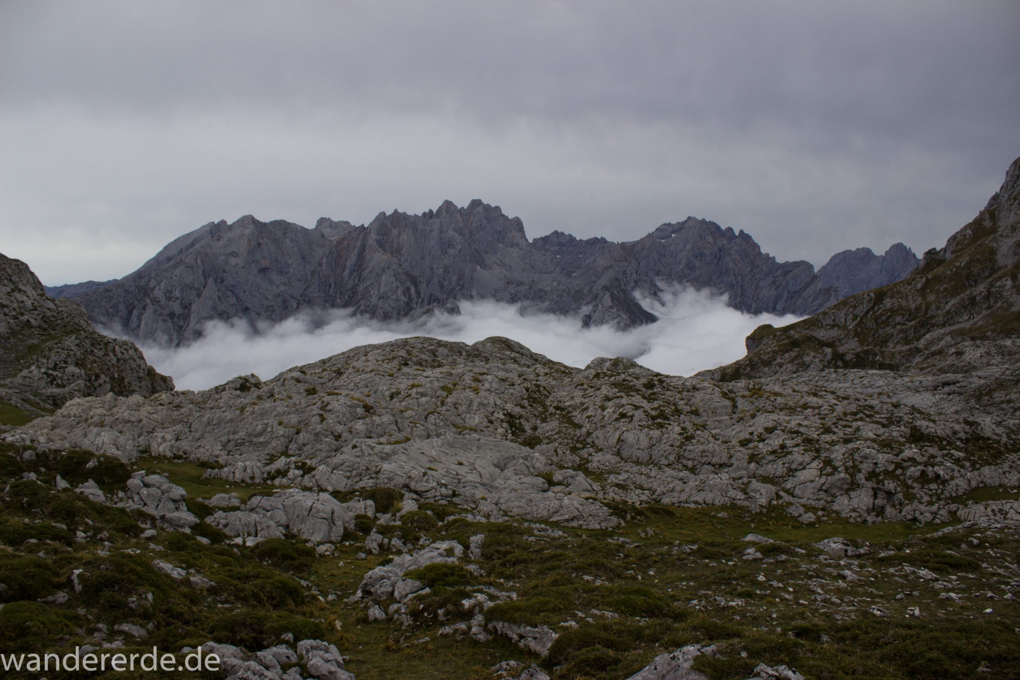 Wanderung Vega de Ario Picos de Europa Spanien, dichte Wolken ziehen auf, Bergregion in Nordspanien, Wandern, zerklüftete Felsen, Steine, schmaler Wanderpfad, atmosphärisch, Aussicht auf große Bergkette