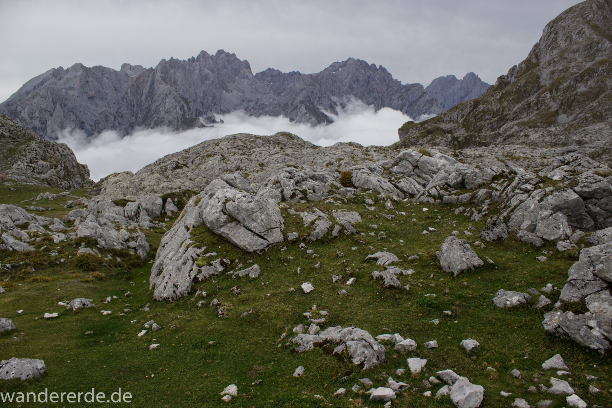 Wanderung Vega de Ario Picos de Europa Spanien, dichte Wolken, Bergregion in Nordspanien, Wandern, zerklüftete Felsen, Steine, schmaler Wanderpfad, atmosphärisch, Aussicht auf große Bergkette, grüne Wiese