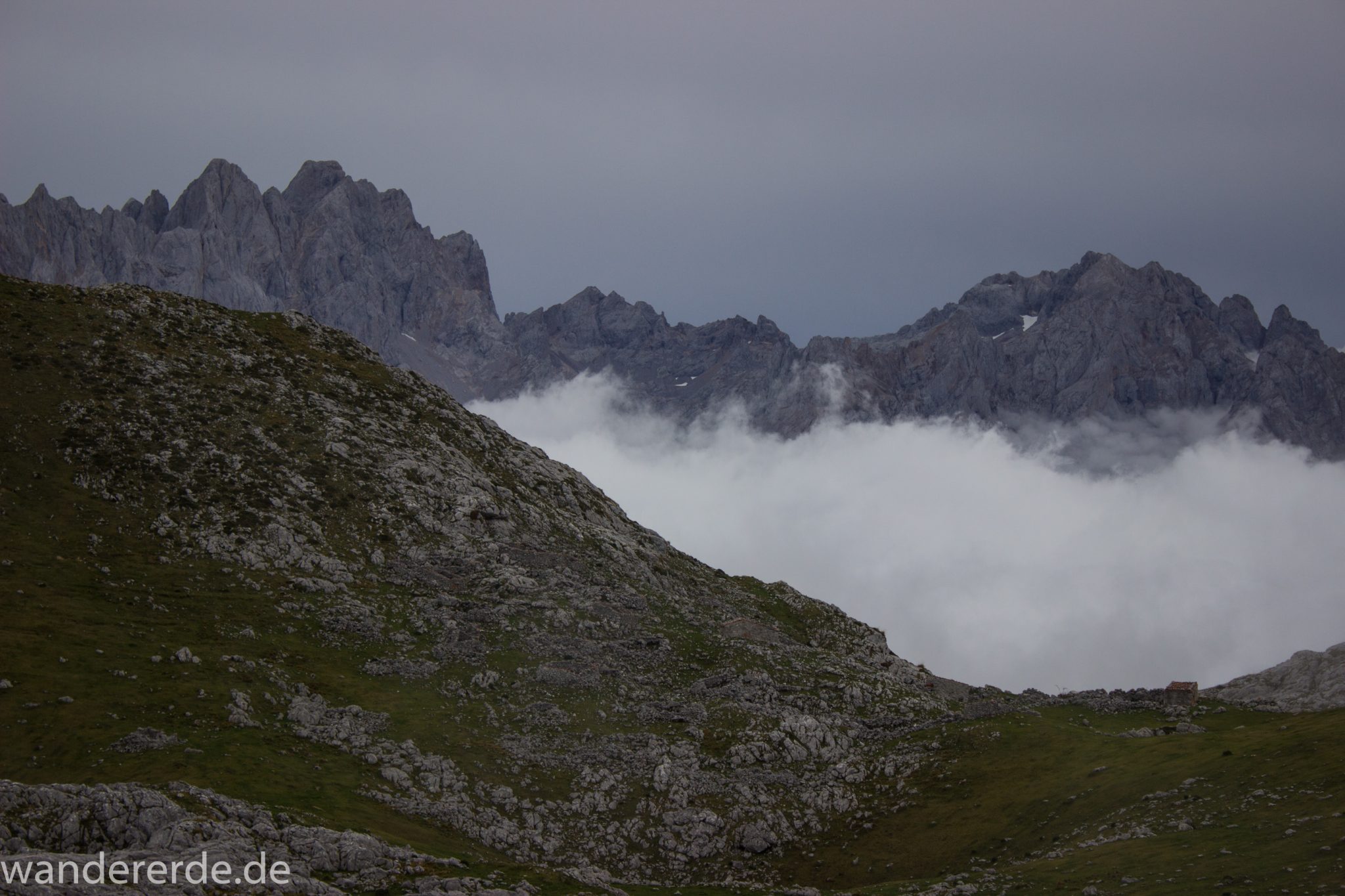 Wanderung Vega de Ario Picos de Europa Spanien, dichte Wolken, Bergregion in Nordspanien, Wandern, zerklüftete Felsen, Steine, schmaler Wanderpfad, atmosphärisch, Aussicht auf große Bergkette, grüne Wiese