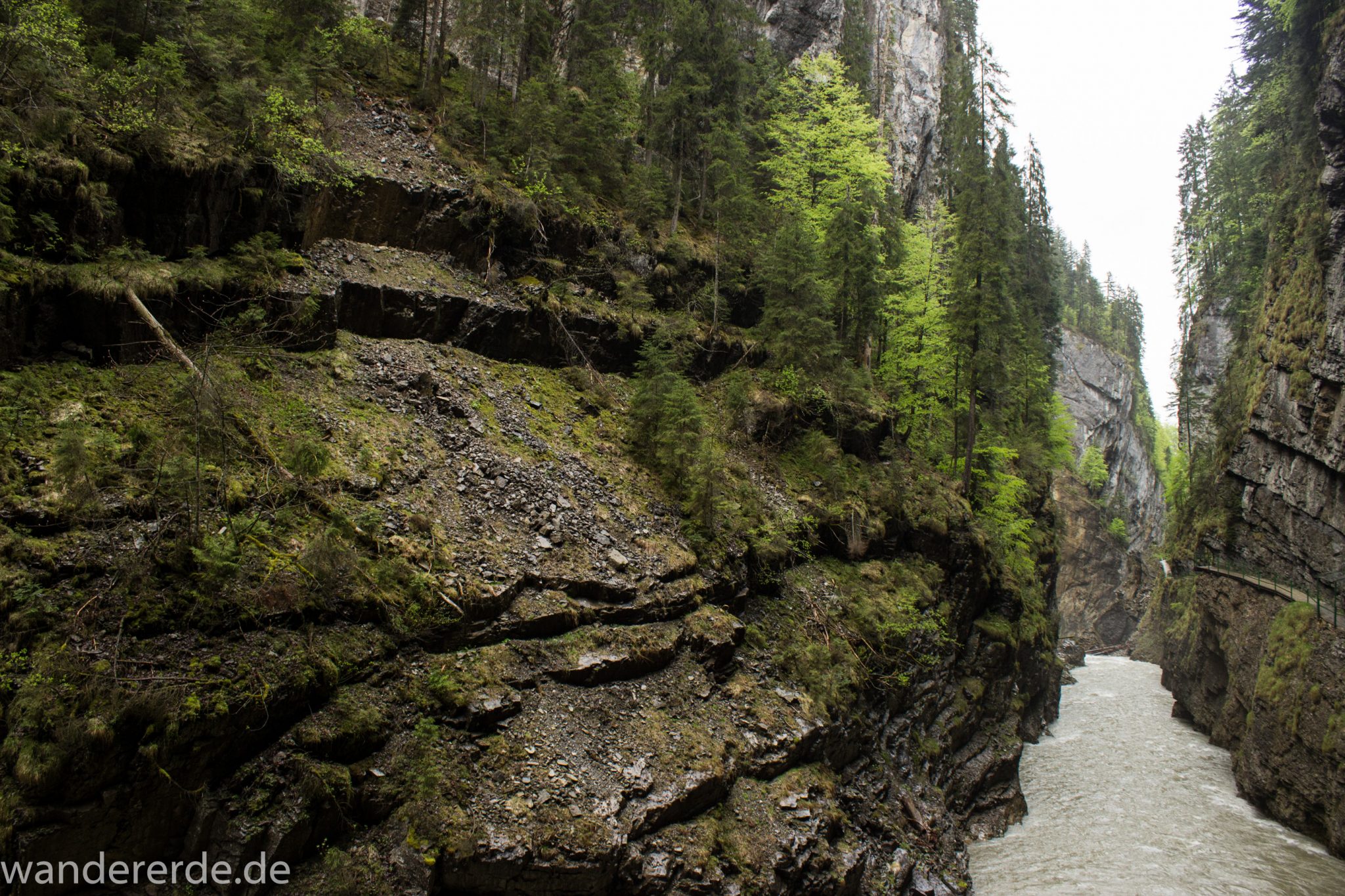 Wanderung durch die Breitachklamm im Allgäu, sehr hohe Felswände, tosende Breitach nach starkem Regen, Klamm umgeben von schönem Wald, Felsen im Fluss, Schneeschmelze im Allgäu, Wanderweg durch die Klamm