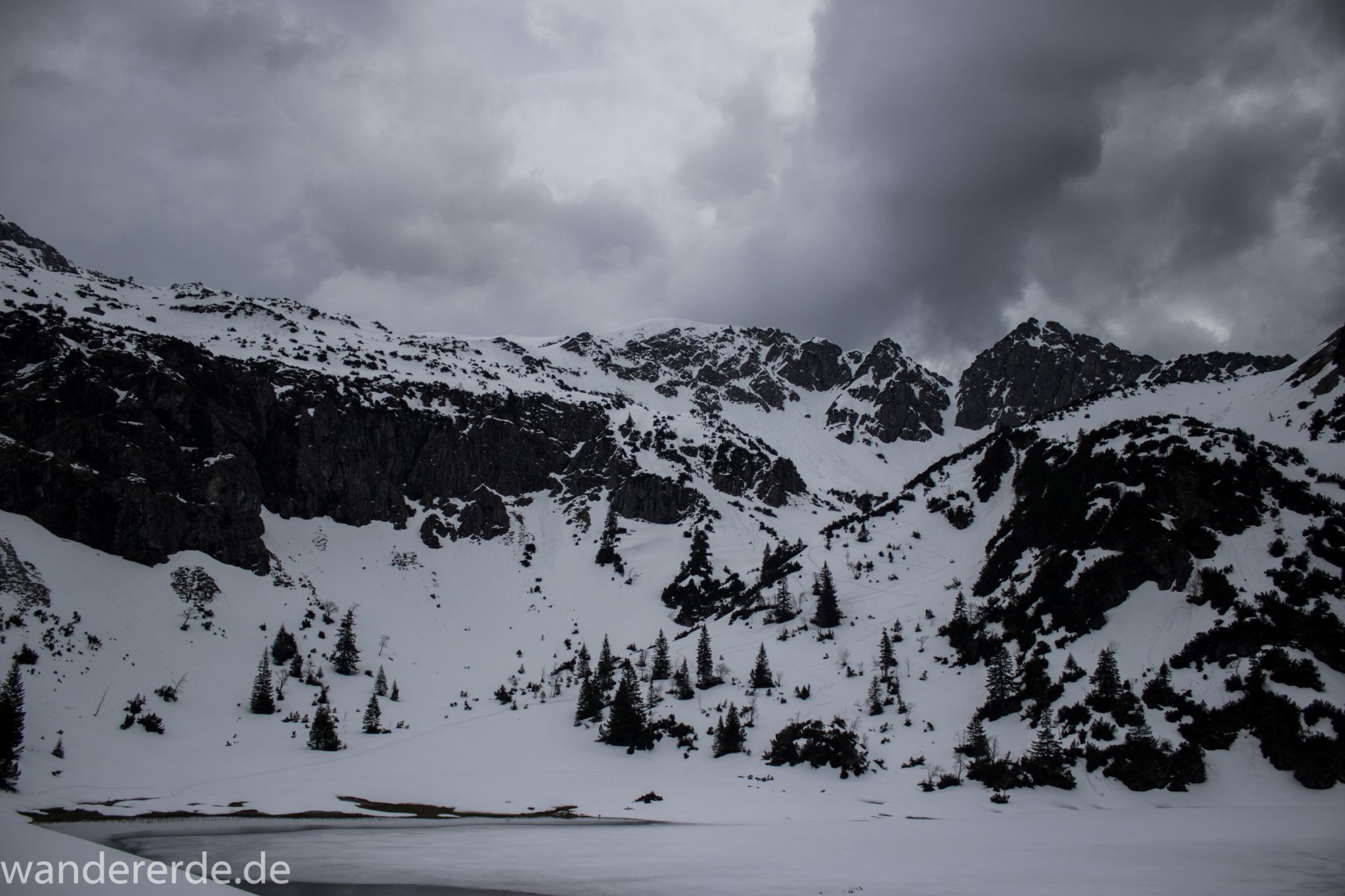 Wanderung Unterer Gaisalpsee, Wanderweg von Oberstdorf im Allgäu, Wanderpfad wird zunehmend schmaler, steil und felsig, weniger Bäume, Blick auf Allgäuer Berge mit Schnee und Unterer Gaisalpsee fast vollständig mit Eis und Schnee bedeckt, Wanderung zu Oberer Gaisalpsee nicht möglich Mitte Mai