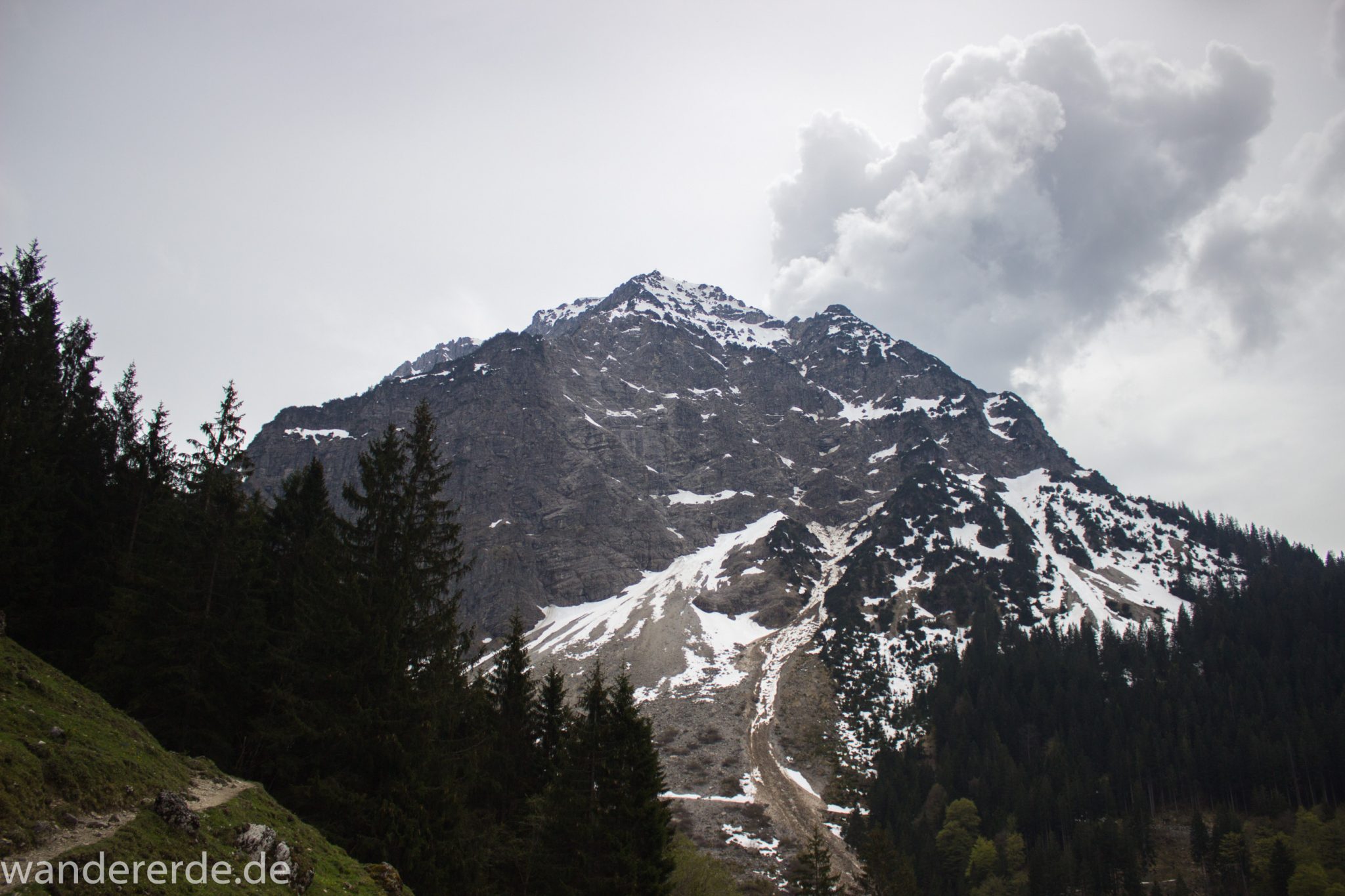 Wanderung Unterer Gaisalpsee, Wanderweg von Oberstdorf im Allgäu, Wanderpfad wird zunehmend schmaler, steil und felsig, umgeben von schönem dichtem Mischwald, Blick auf Allgäuer Berge mit Schnee in der Ferne