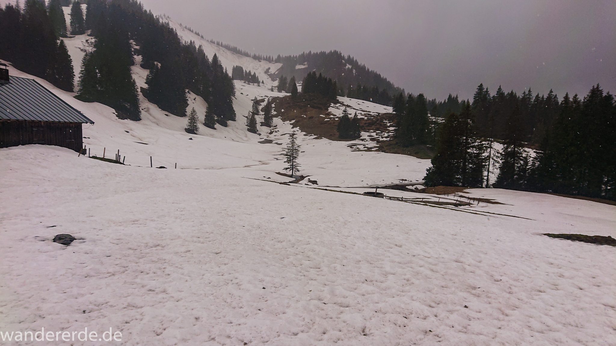 Wandern Gunzesrieder Ostertal im Allgäu, Baden-Württemberg, Obere Älple, viel Regen, dunkle Wolken, sehr viel Schnee im Mai, saftig grüner Wald, Wanderweg unter Schnee, schöne Atmosphäre und Aussicht
