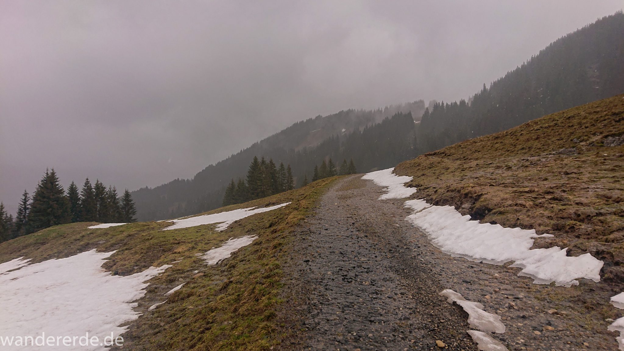Wandern Gunzesrieder Ostertal im Allgäu, Baden-Württemberg, Obere Älple, viel Regen, dunkle Wolken, Schnee im Mai, saftig grüner Wald, Wanderweg unter Schnee, schöne Atmosphäre und Aussicht