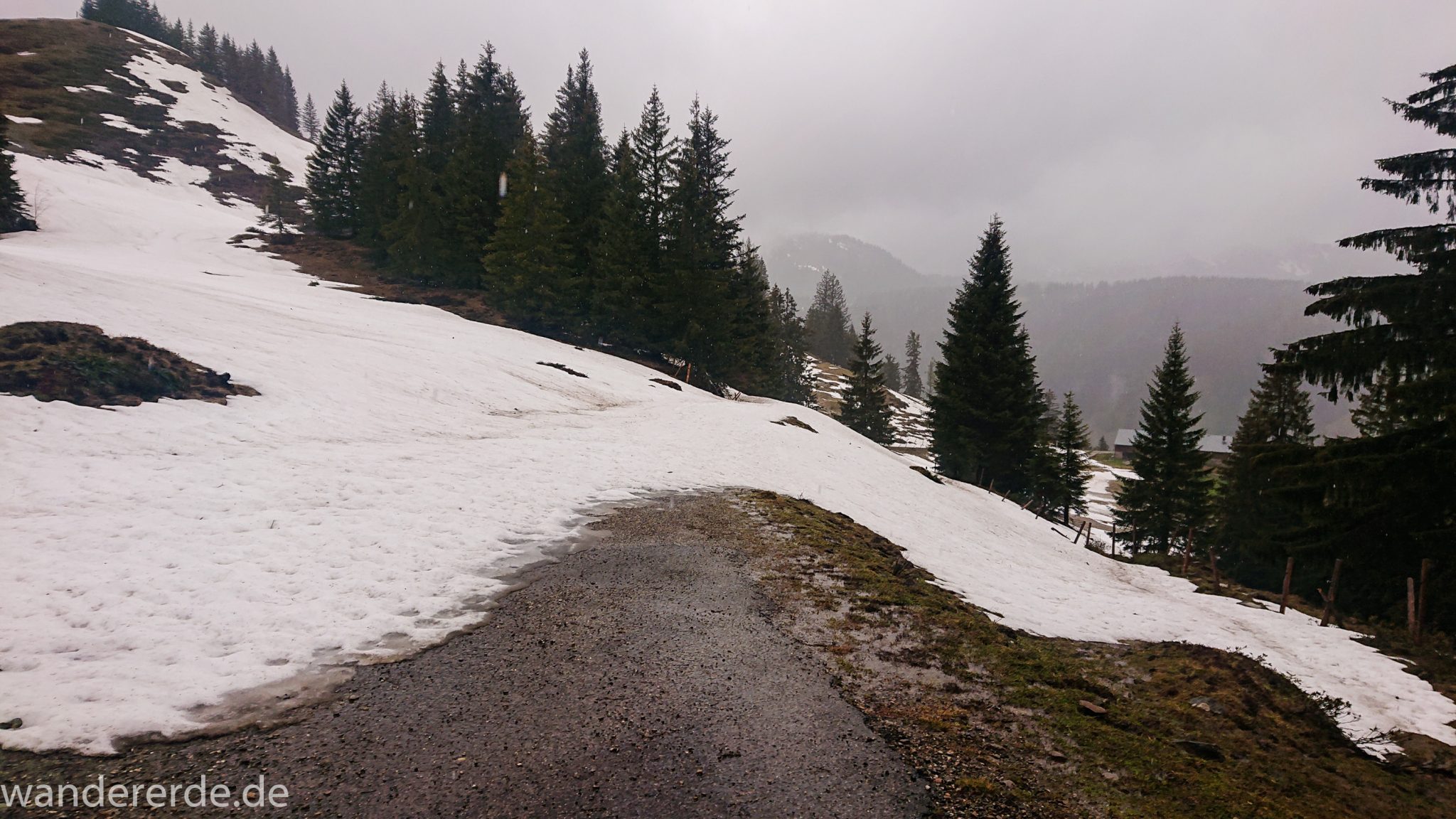 Wandern Gunzesrieder Ostertal im Allgäu, Baden-Württemberg, Obere Älple, viel Regen, dunkle Wolken, Schnee im Mai, saftig grüner Wald, Wanderweg unter Schnee