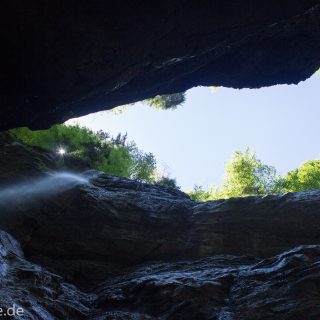Rundwanderung Partnachklamm im Wettersteingebirge bei Garmisch-Partenkirchen, Bayern, steil aufragende Felswände, Licht strahlt von oben in die Klamm, kühl und nass, an Felswand bildet sich kleiner Wasserfall, oberhalb der Partnachklamm wächst schöner, dichter Wald