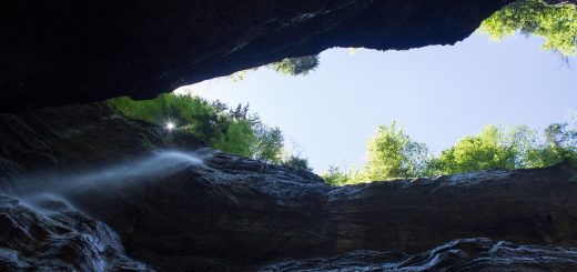 Rundwanderung Partnachklamm im Wettersteingebirge bei Garmisch-Partenkirchen, Bayern, steil aufragende Felswände, Licht strahlt von oben in die Klamm, kühl und nass, an Felswand bildet sich kleiner Wasserfall, oberhalb der Partnachklamm wächst schöner, dichter Wald