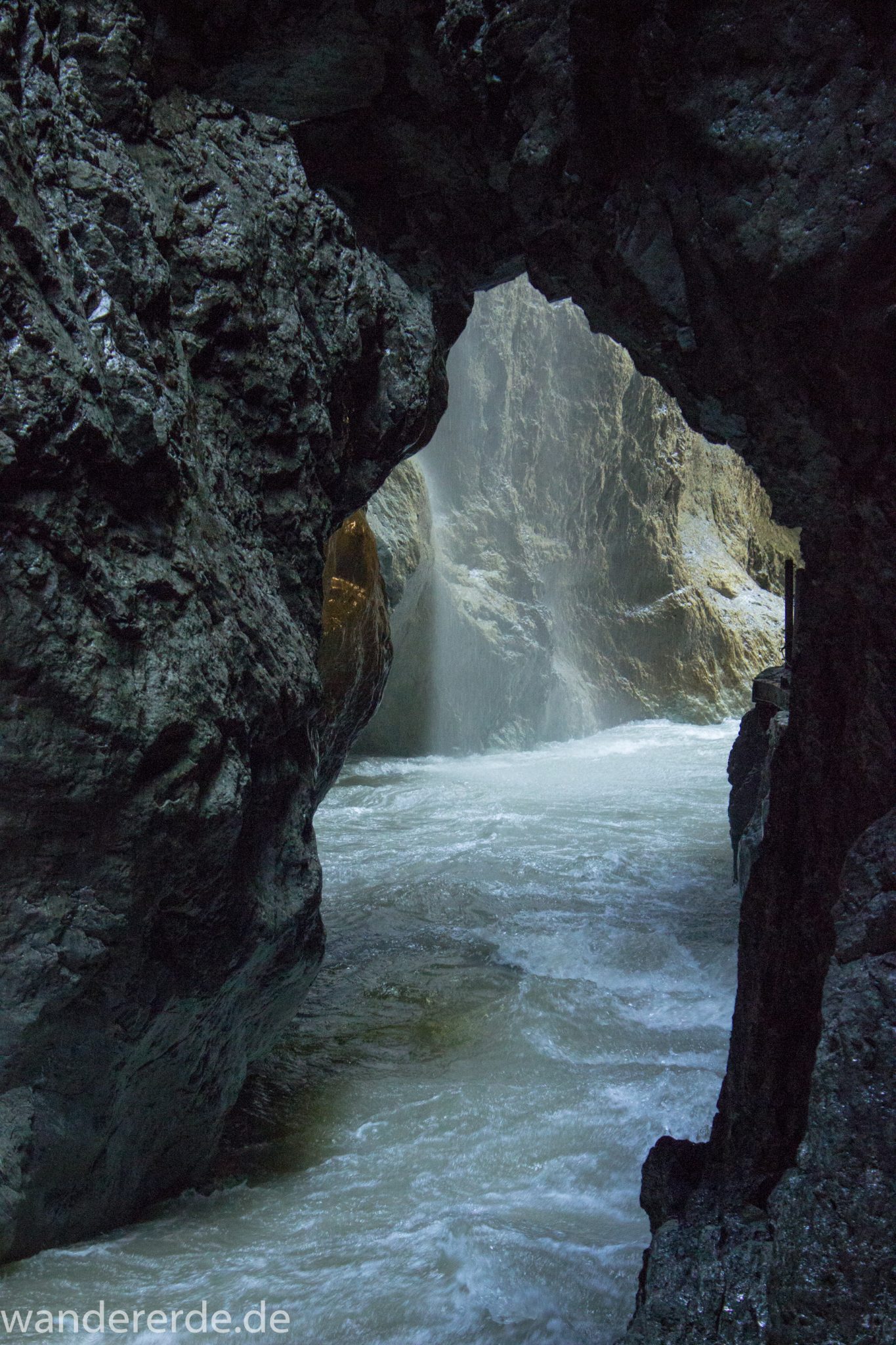 Rundwanderung Partnachklamm im Wettersteingebirge bei Garmisch-Partenkirchen, Bayern, steil aufragende Felswände in enger Schlucht, Licht strahlt von einem Ende in die Klamm, kühl und nass, Fluss Partnach bahnt sich seinen Weg durch die Klamm