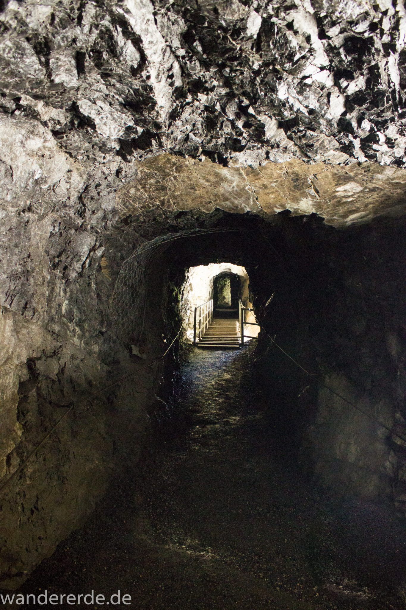 Rundwanderung Partnachklamm im Wettersteingebirge bei Garmisch-Partenkirchen, Bayern, dunkler, gesicherter Wanderweg führt durch den Fels, Wanderweg durch Felssprengung, kühl und nass