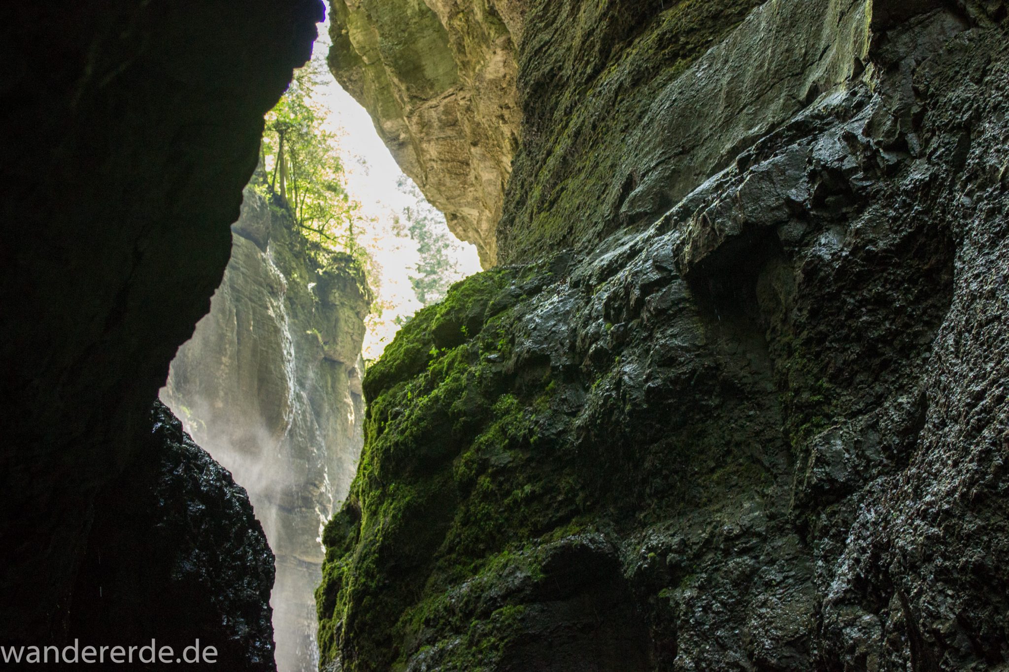 Rundwanderung Partnachklamm im Wettersteingebirge bei Garmisch-Partenkirchen, Bayern, steil aufragende Felswände, moosbedeckter Fels, Licht strahlt durch Eingang der Klamm