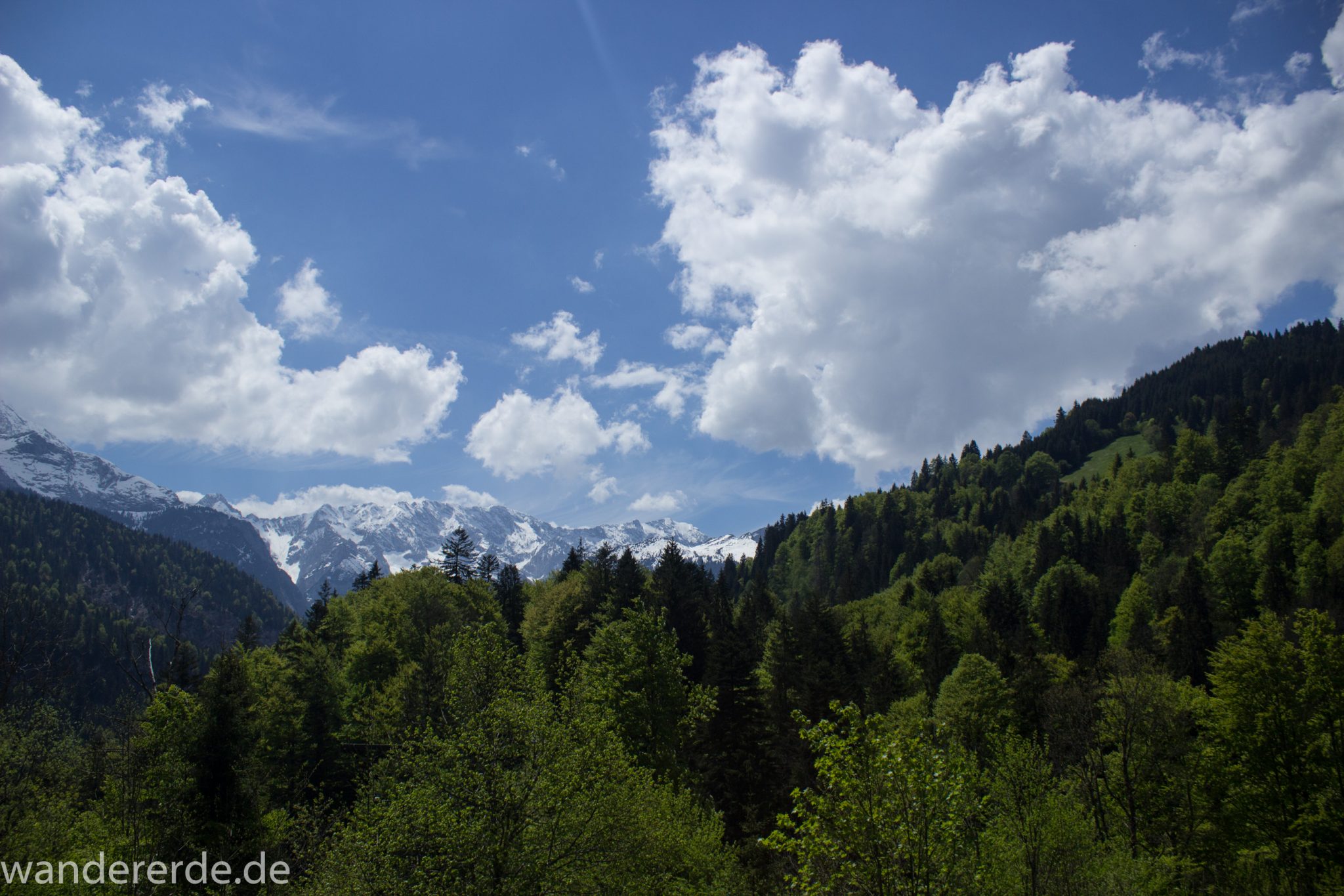Rundwanderung Partnachklamm im Wettersteingebirge bei Garmisch-Partenkirchen, Bayern, Wanderweg hinter der Partnachklamm führt durch schönen, dichten Mischwald, die Sonne wärmt wieder nachdem es in der Klamm ziemlich kühl war, in der Ferne Blick auf schneebedeckte Berge