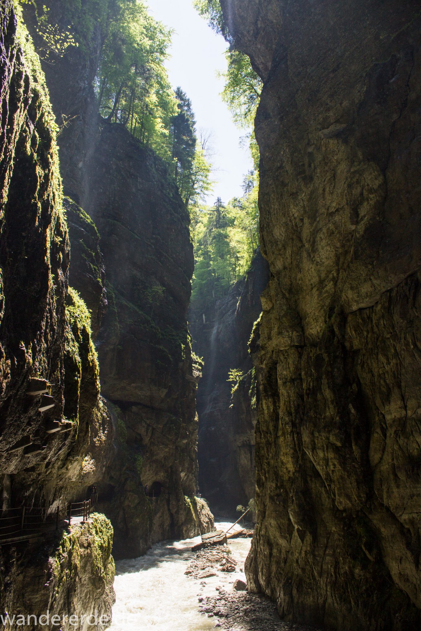 Rundwanderung Partnachklamm im Wettersteingebirge bei Garmisch-Partenkirchen, Bayern, steil aufragende Felswände, Licht strahlt von oben in die Klamm, gesicherter Wanderweg in den Fels gehauen, kühl und nass