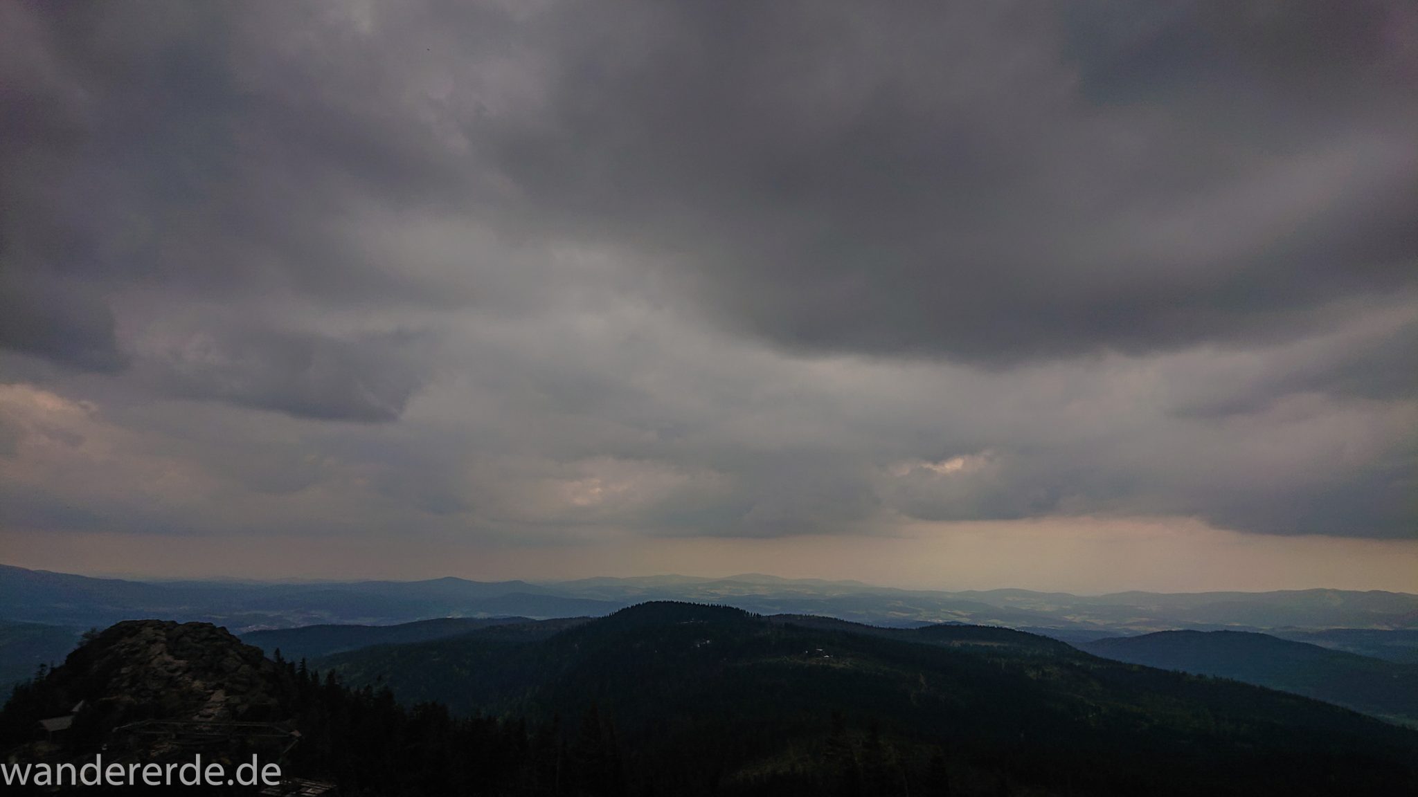 Rundwanderung zum Großen Arber im Bayerischen Wald, weite Aussicht auf riesiges Waldgebiet des bayerischen Waldes vom Berg Großer Arber, schöner und dichter Wald, Mischwald aus Laub- und Nadelbäume, Frühjahr im bayerischen Wald, sehr stimmungsvolles Licht durch dunkle Wolken und späten Tag