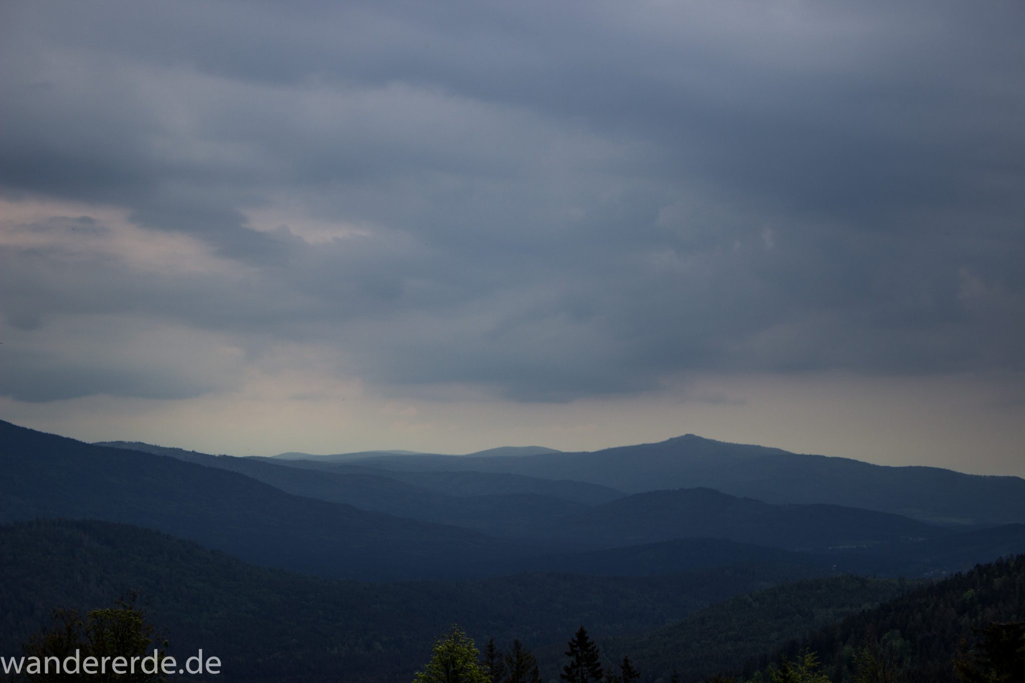 Rundwanderung zum Großen Arber im Bayerischen Wald, weite Aussicht auf riesiges Waldgebiet des bayerischen Waldes vom Berg Großer Arber, schöner und dichter Wald, Mischwald aus Laub- und Nadelbäume, Frühjahr im bayerischen Wald, sehr stimmungsvolles Licht durch dunkle Wolken und späten Tag