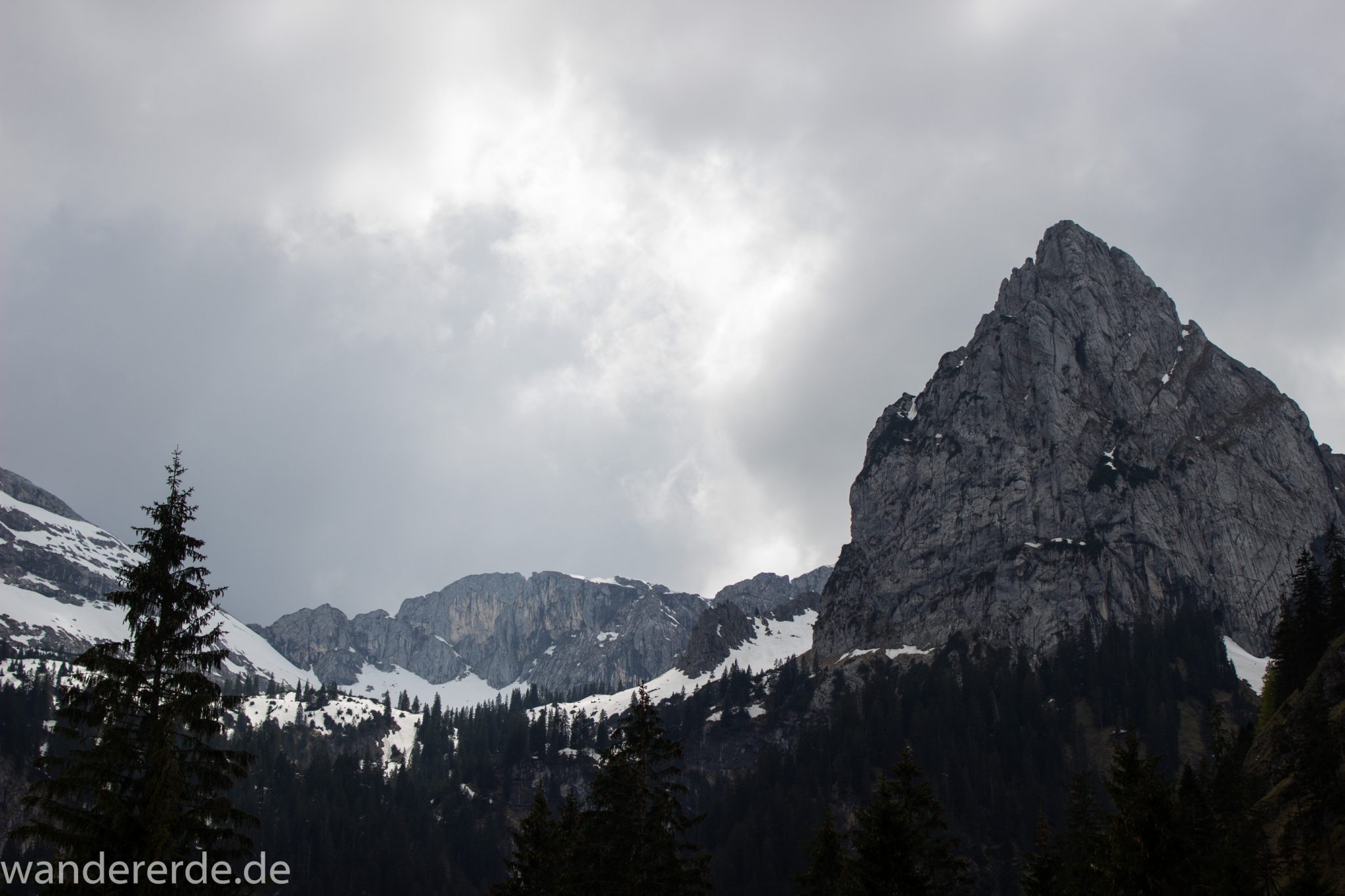 Wanderung zur Kenzenhütte in den Ammergauer Alpen, Aussicht auf die teils schneebedeckten Berge, spitzer Gipfel, Frühjahr in den bayerischen Alpen, sehr atmosphärisch durch dichte Wolkenfelder