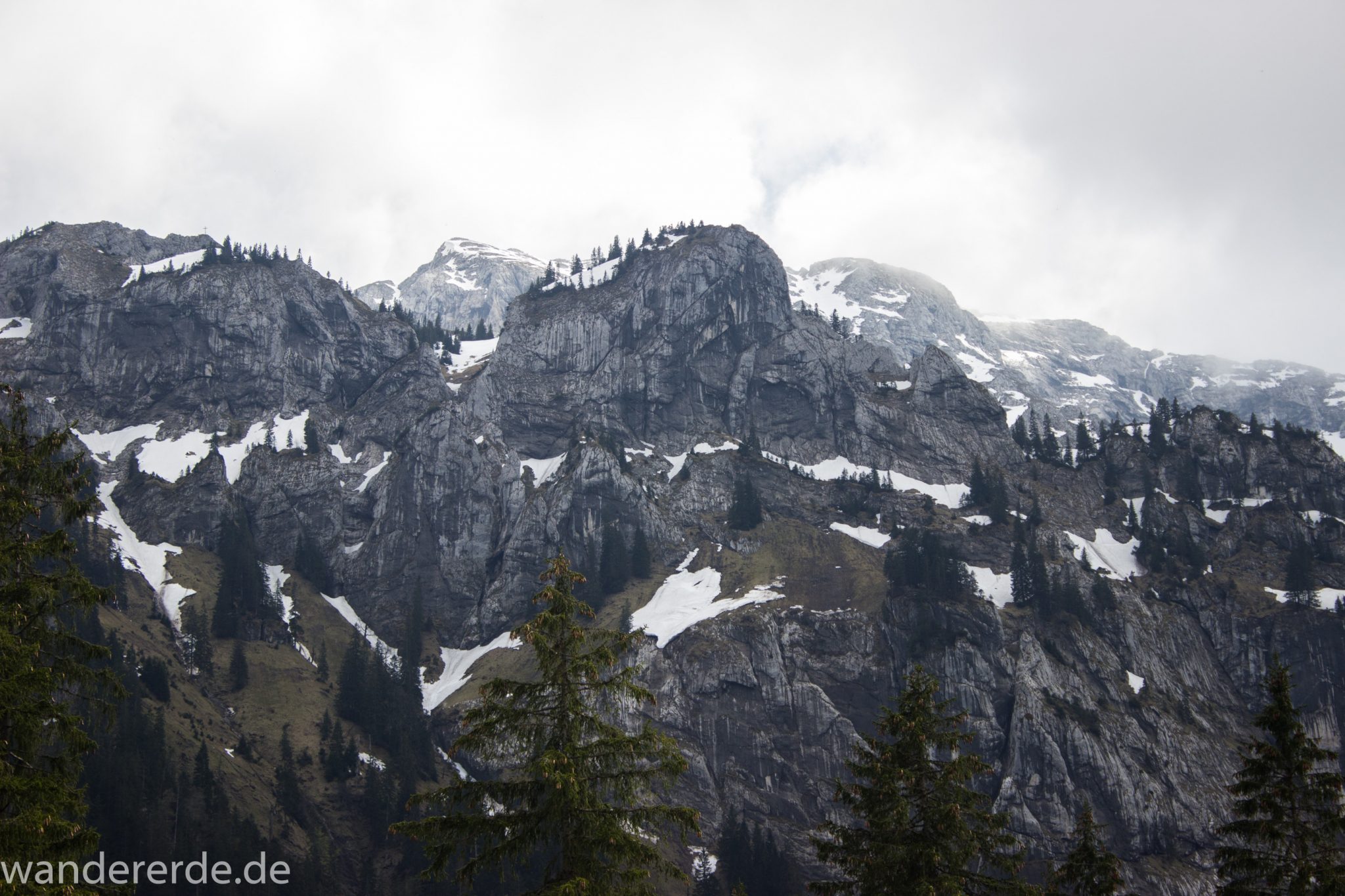 Wanderung zur Kenzenhütte in den Ammergauer Alpen, Aussicht auf die teils schneebedeckten Berge, Frühjahr in den bayerischen Alpen, sehr atmosphärisch durch dichte Wolkenfelder, schöner dichter Wald