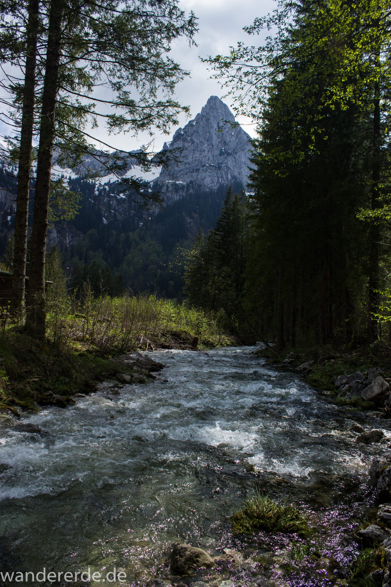 Wanderung zur Kenzenhütte in den Ammergauer Alpen, Aussicht auf die Berge mit imposantem Berggipfel, teils schneebedeckte Berge in Wolken gehüllt, Frühjahr in den bayerischen Alpen, dichter grüner Wald und saftige Wiesen, Wanderweg oftmals am schönen, idyllischem Fluss entlang