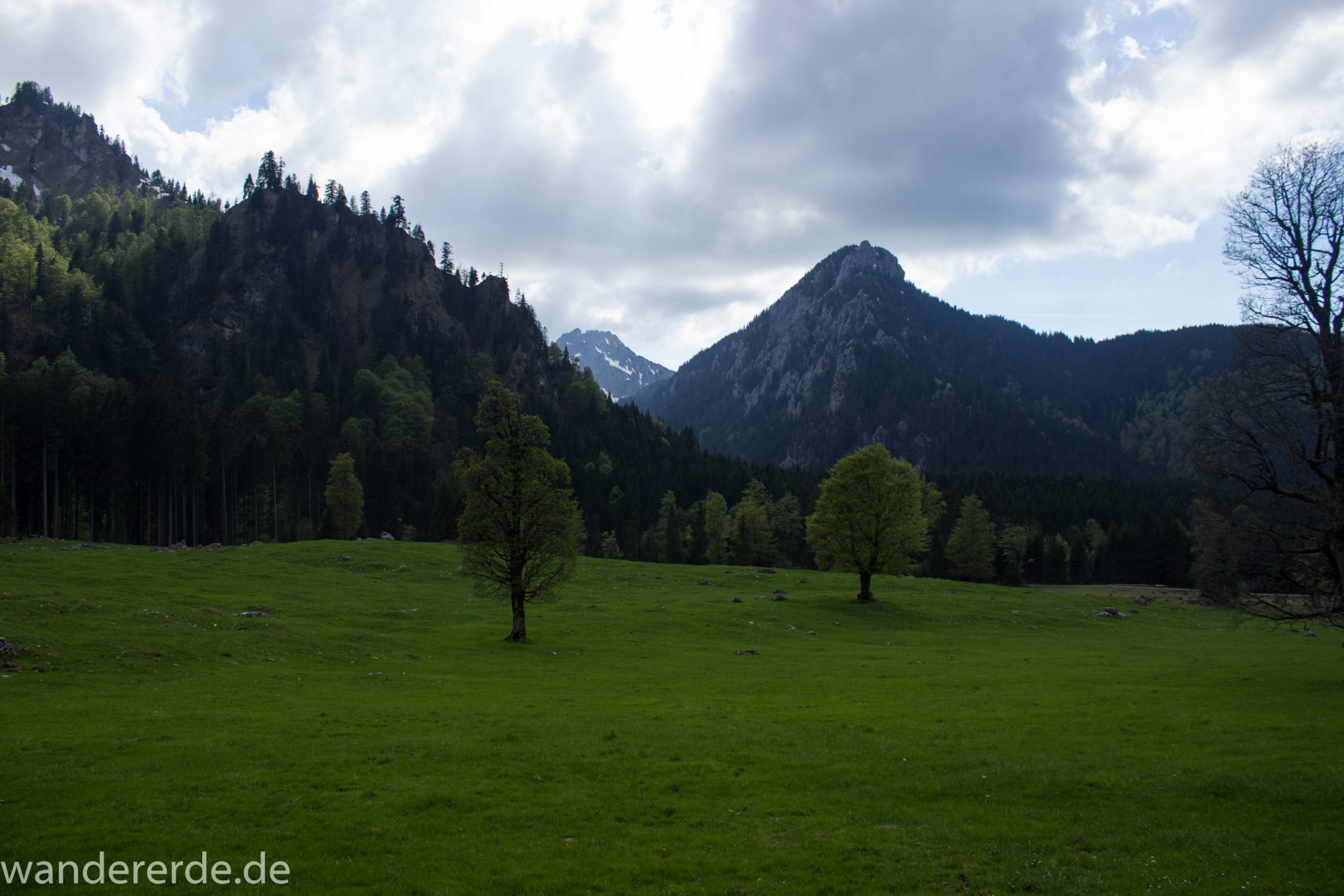 Wanderung zur Kenzenhütte in den Ammergauer Alpen, Aussicht auf die teils schneebedeckten Berge, Frühjahr in den bayerischen Alpen, Wanderweg führt entlang dichtem grünen Wald und saftigen Wiesen