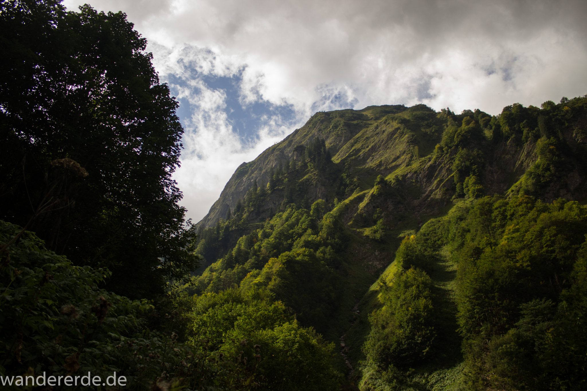 Alpenüberquerung Fernwanderweg E5 Oberstdorf Meran, 1. Etappe von Oberstdorf zur Kemptner Hütte, Wanderweg führt von der Spielmannsau bei Oberstdorf im Allgäu zur Kemptner Hütte  entlang eines schmalen Wanderpfads umgeben von saftig grüner Vegetation, schöner, dichter Wald, Aussicht auf die Berge im Allgäu, Bayern
