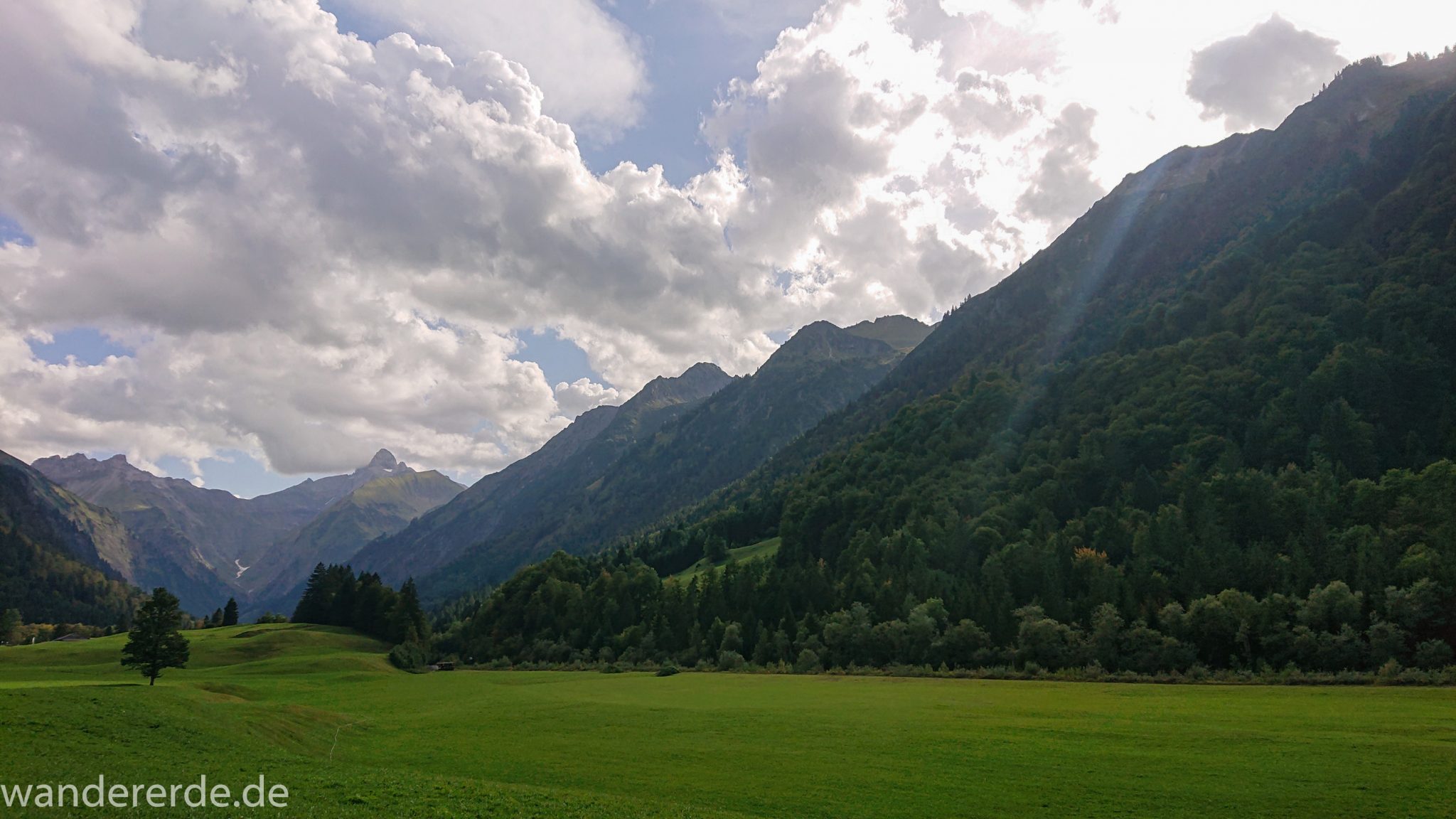 Alpenüberquerung Fernwanderweg E5 Oberstdorf Meran, 1. Etappe von Oberstdorf zur Kemptner Hütte, Wanderweg von Oberstdorf zur Spielmannsau führt entlang saftig grüner Wiesen im Allgäu umgeben von grünem Wald, Aussicht auf die Berge im Allgäu