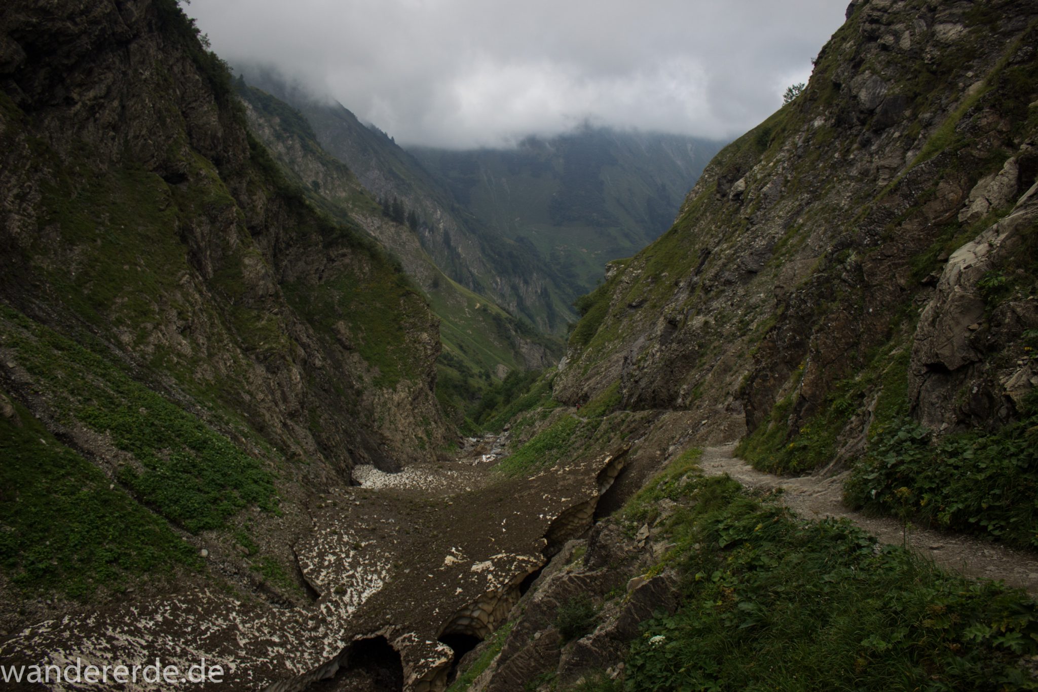 Alpenüberquerung Fernwanderweg E5 Oberstdorf Meran, 1. Etappe von Oberstdorf zur Kemptner Hütte, Wanderweg führt von der Spielmannsau bei Oberstdorf im Allgäu zur Kemptner Hütte entlang eines schmalen Wanderpfads über Stock und Stein, Weg durch Sperrbachtobel mit Schnee, Schlucht umgeben von hohen Felswänden in den Bergen, Wegverlauf zunehmend ansteigend, teilweise steil