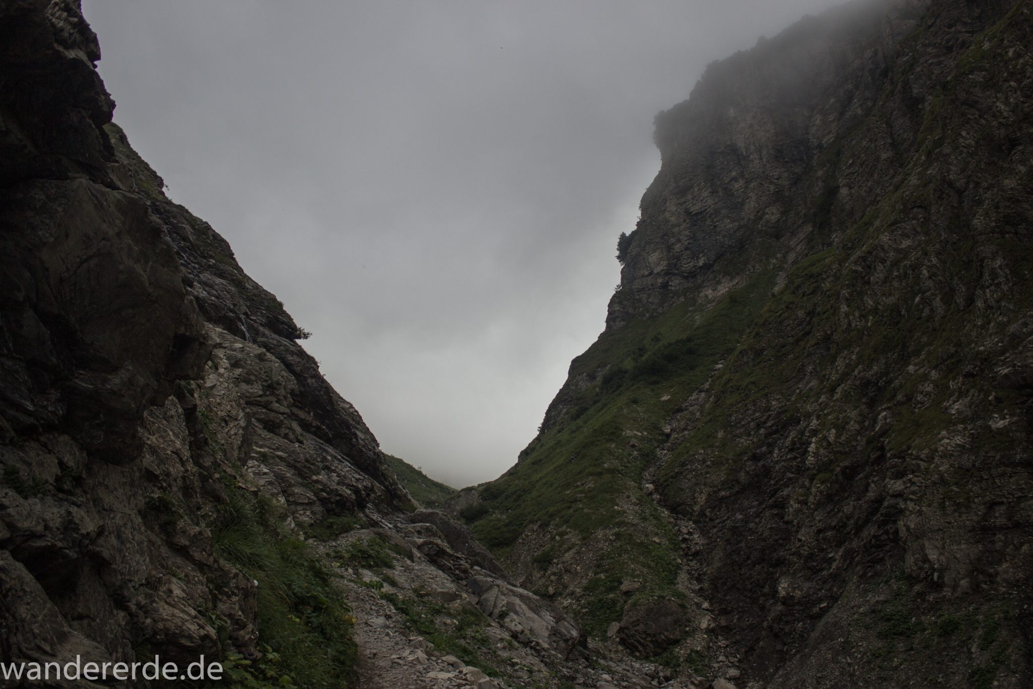 Alpenüberquerung Fernwanderweg E5 Oberstdorf Meran, 1. Etappe von Oberstdorf zur Kemptner Hütte, Wanderweg führt von der Spielmannsau bei Oberstdorf im Allgäu zur Kemptner Hütte entlang eines schmalen Wanderpfads über Stock und Stein, Weg durch Sperrbachtobel mit Schnee, Schlucht umgeben von hohen Felswänden in den Bergen, Wegverlauf zunehmend ansteigend, teilweise steil