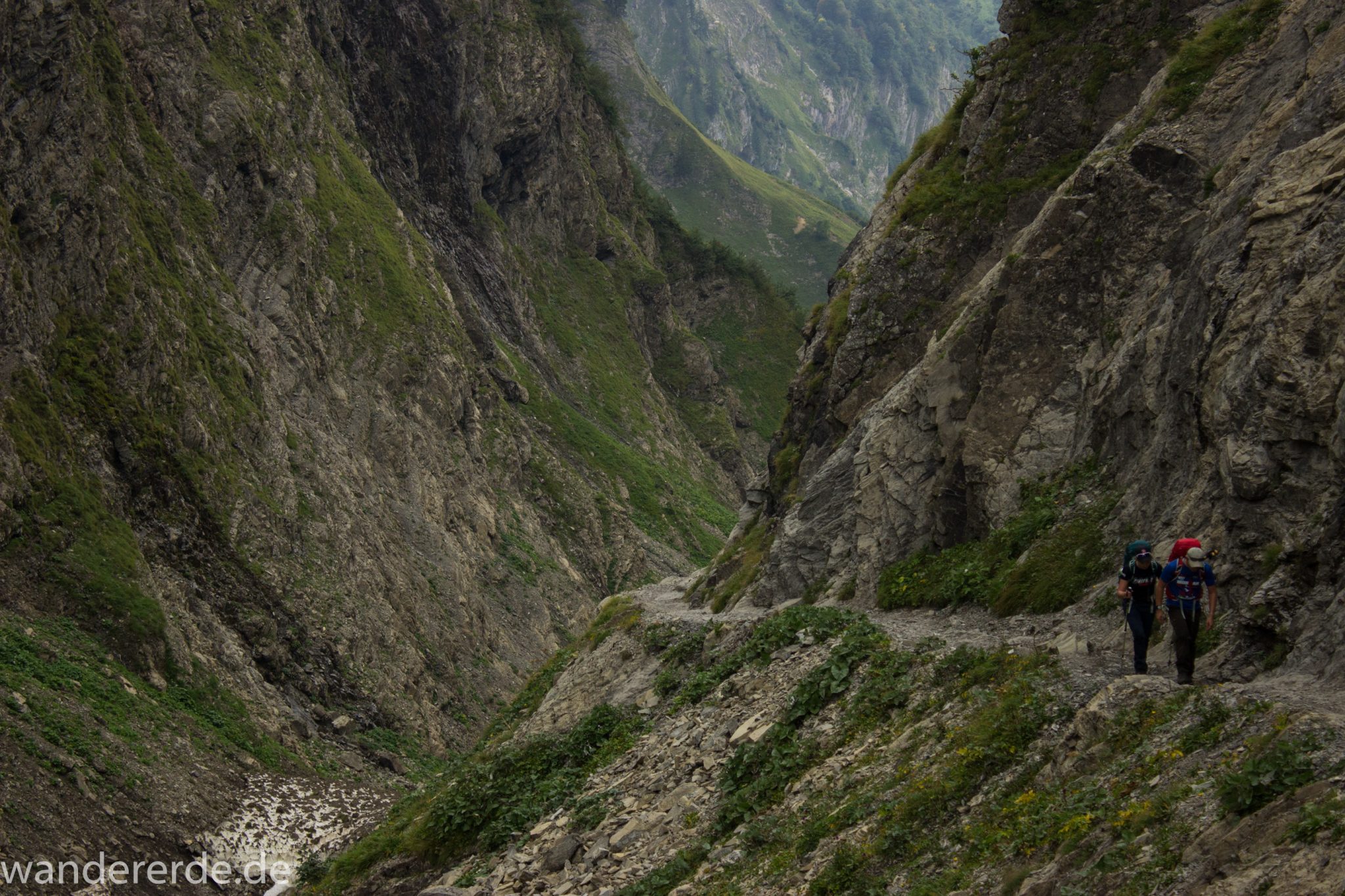 Alpenüberquerung Fernwanderweg E5 Oberstdorf Meran, 1. Etappe von Oberstdorf zur Kemptner Hütte, Wanderweg führt von der Spielmannsau bei Oberstdorf im Allgäu zur Kemptner Hütte entlang eines schmalen Wanderpfads über Stock und Stein, Weg durch Sperrbachtobel mit Schnee, Schlucht umgeben von hohen Felswänden in den Bergen, Wegverlauf zunehmend ansteigend, teilweise steil