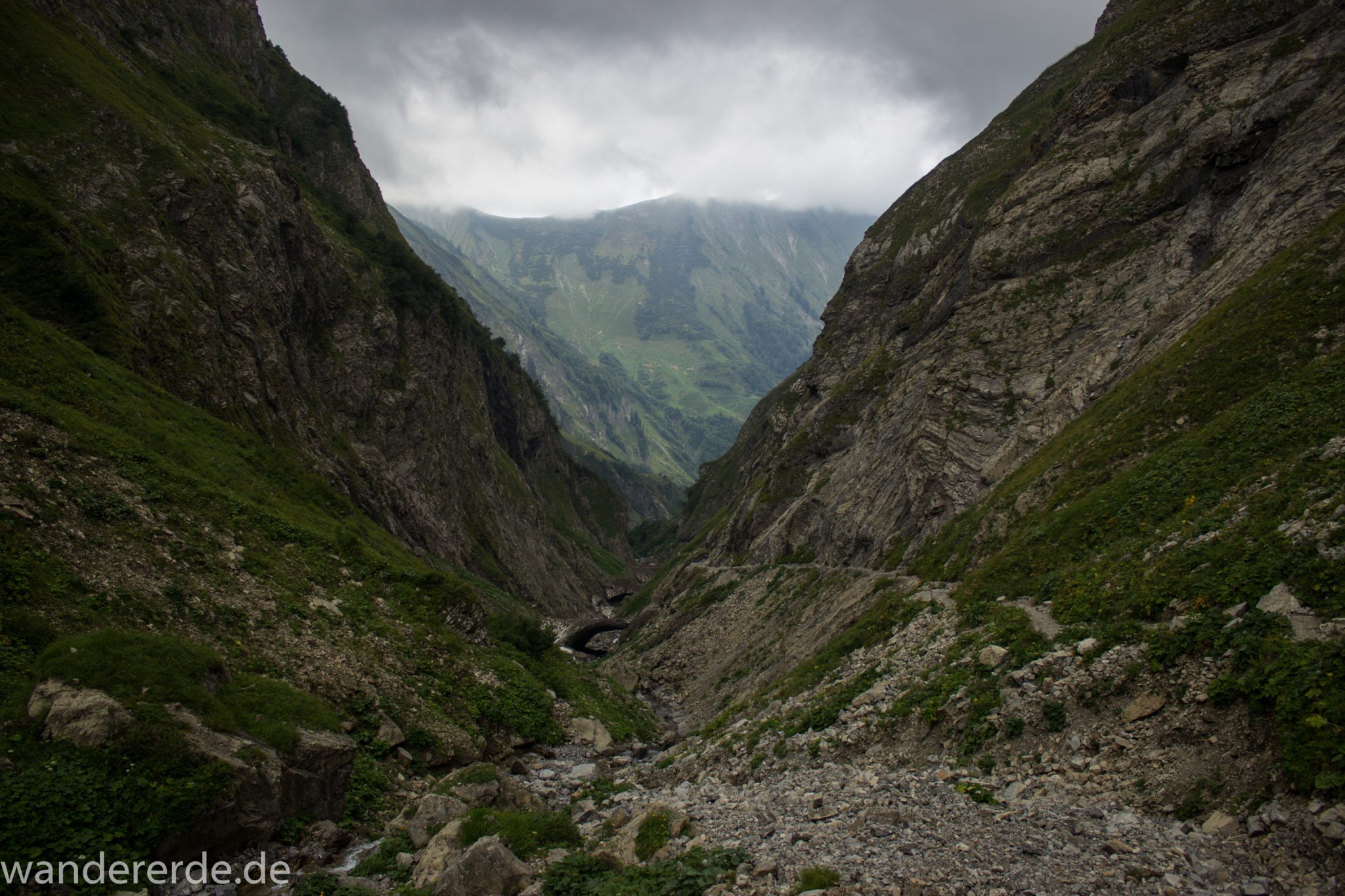 Alpenüberquerung Fernwanderweg E5 Oberstdorf Meran, 1. Etappe von Oberstdorf zur Kemptner Hütte, Wanderweg führt von der Spielmannsau bei Oberstdorf im Allgäu zur Kemptner Hütte entlang eines schmalen Wanderpfads über Stock und Stein, Weg durch Sperrbachtobel mit Schnee, Schlucht umgeben von hohen Felswänden in den Bergen, Wegverlauf zunehmend ansteigend, teilweise steil