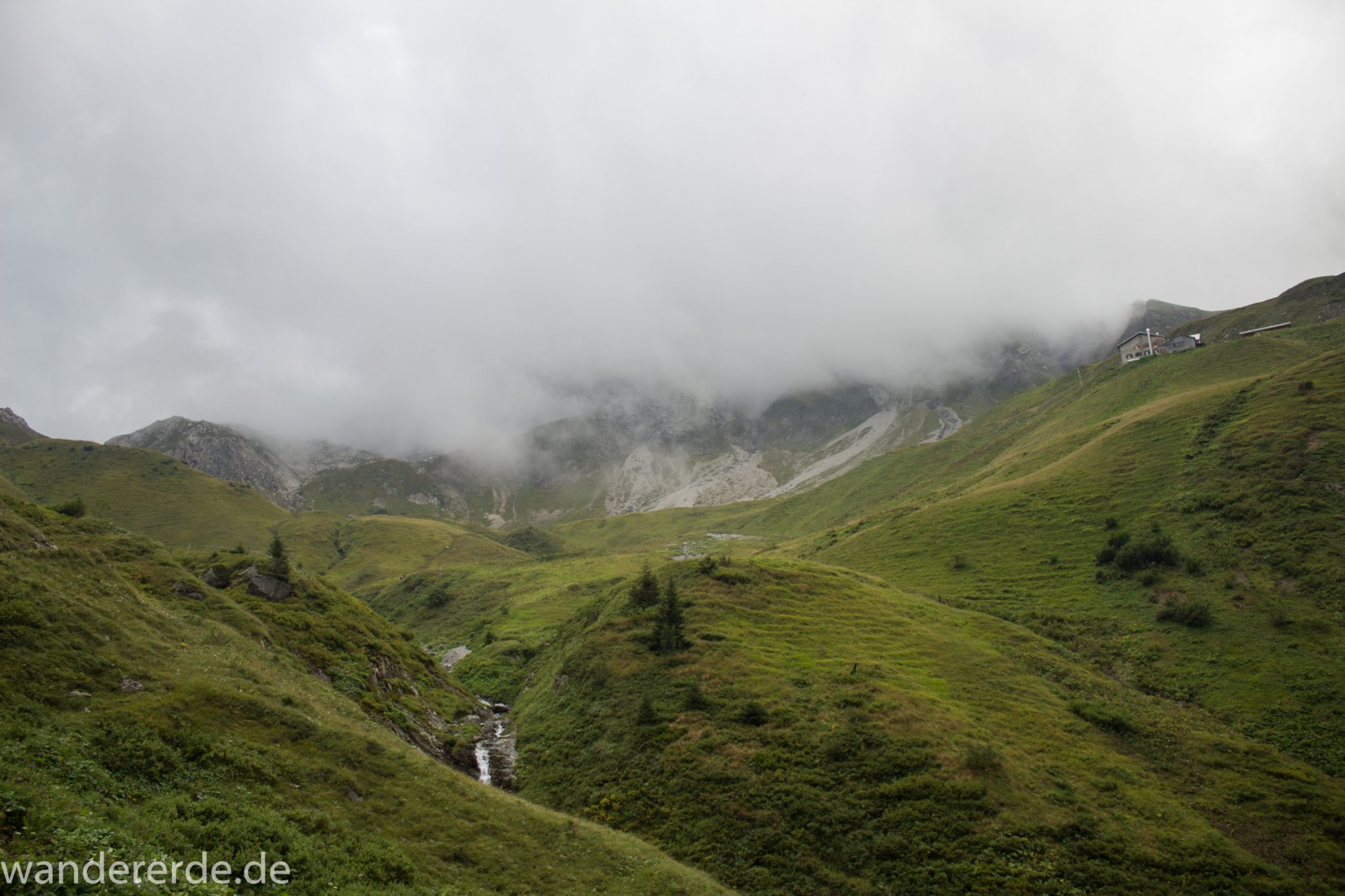 Alpenüberquerung Fernwanderweg E5 Oberstdorf Meran, 1. Etappe von Oberstdorf zur Kemptner Hütte, Wanderweg führt von der Spielmannsau bei Oberstdorf im Allgäu zur Kemptner Hütte entlang eines schmalen Wanderpfads über Stock und Stein, Weg durch Sperrbachtobel mit saftig güner Vegetation, Sicht auf schöne Berge im Nebel und Blick auf die Kemptner Hütte, Wegverlauf zunehmend ansteigend, teilweise steil