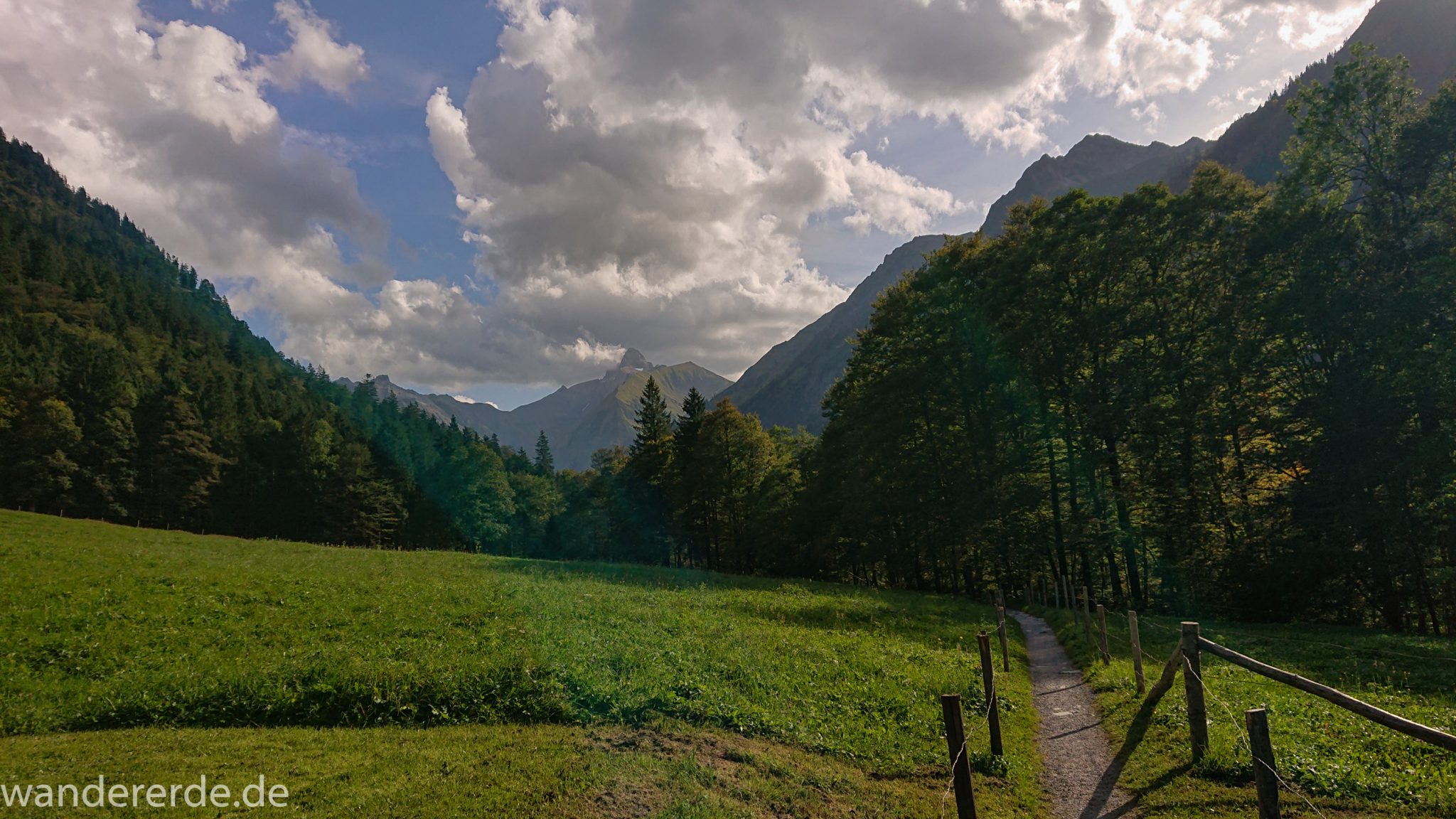 Alpenüberquerung Fernwanderweg E5 Oberstdorf Meran, 1. Etappe von Oberstdorf zur Kemptner Hütte, Wanderweg von Oberstdorf zur Spielmannsau führt entlang saftig grüner Wiesen im Allgäu umgeben von grünem Wald, Aussicht auf die Berge im Allgäu, Bayern