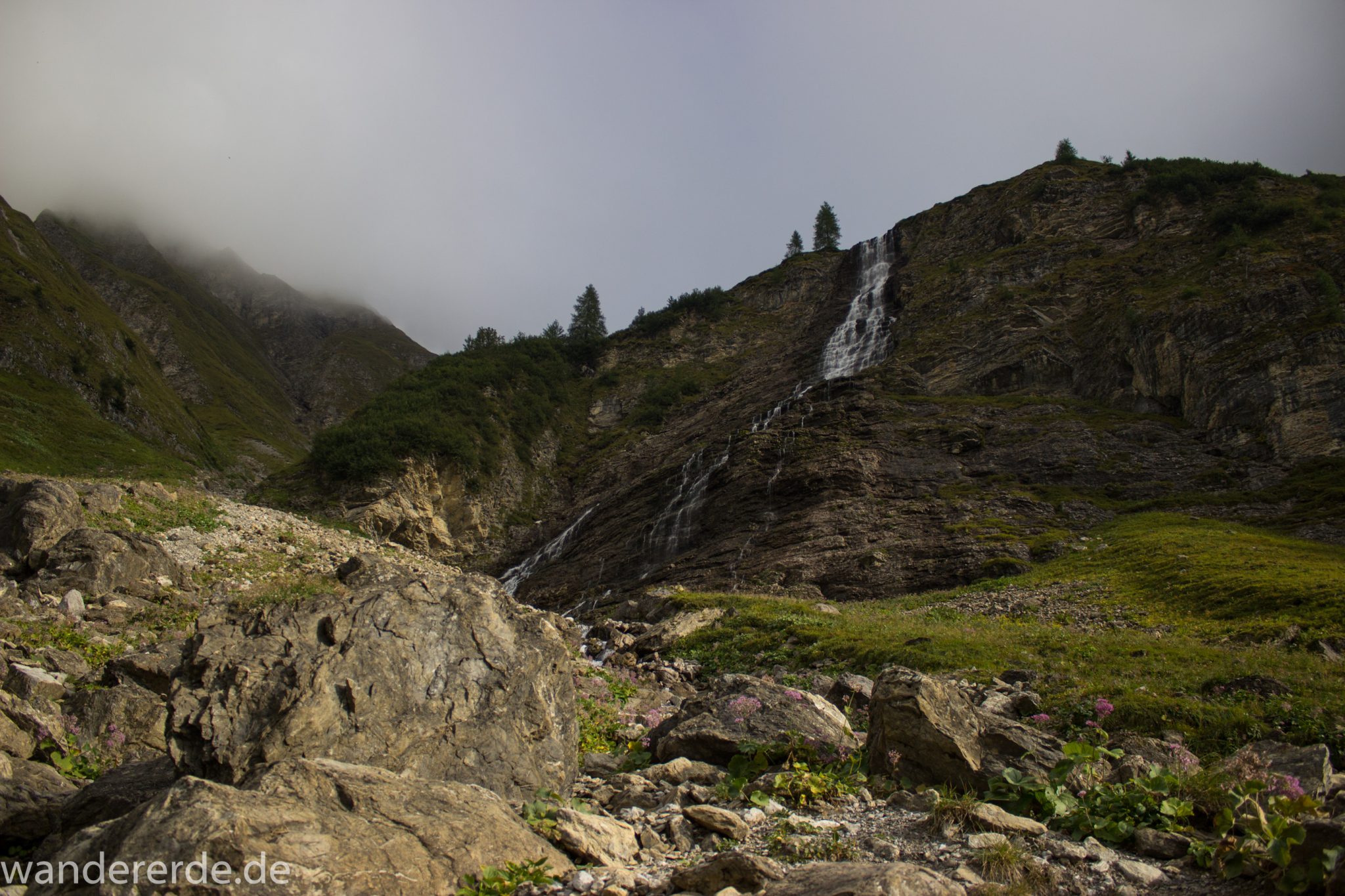 Alpenüberquerung Fernwanderweg E5 Oberstdorf Meran, 2. Etappe von Kemptner Hütte zur Memminger Hütte, schöner abwechslungsreicher und schmaler Wanderweg führt über Stock und Stein ab der Materialseilbahn der Memminger Hütte zunächst mäßig, dann steiler bergauf zur Memminger Hütte, idyllische Landschaft öffnet sich zu flacherer Ebene mit saftig grünen Wiesen und führt zum schönen Wasserfall umgeben von beeindruckenden Bergen und rundum schöner Aussicht