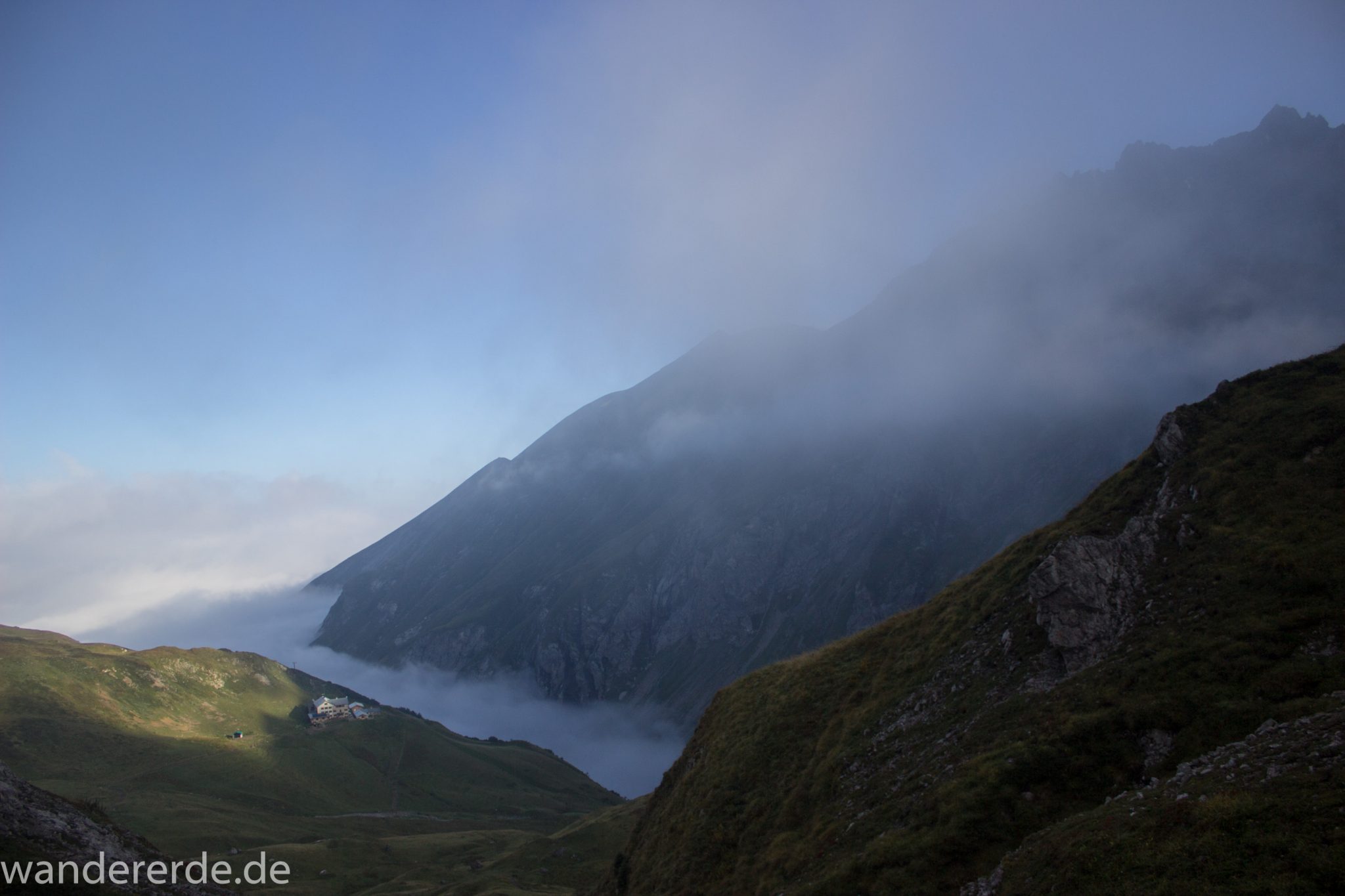 Alpenüberquerung Fernwanderweg E5 Oberstdorf Meran, 2. Etappe von Kemptner Hütte zur Memminger Hütte, Aussicht auf die Kemptner Hütte beim Aufstieg zum Mädelejoch, umliegende Berge in Wolken gehüllt, weitere Wanderung mit eingeschränkter Sicht wegen Nebel, beeindruckende Landschaft in den Bergen