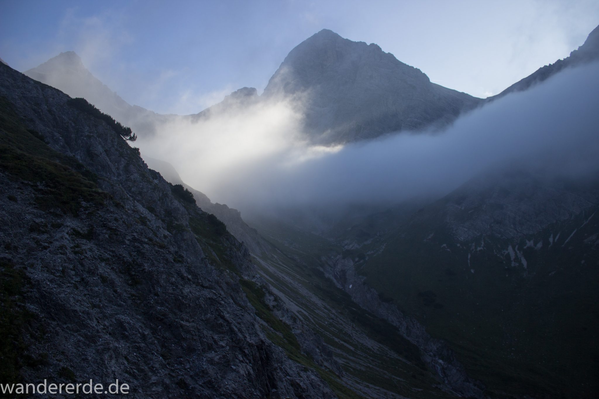 Alpenüberquerung Fernwanderweg E5 Oberstdorf Meran, 2. Etappe von Kemptner Hütte zur Memminger Hütte, Aussicht in der Nähe vom Mädelejoch, umliegende Berge in Wolken gehüllt, Berggipfel sichtbar, weitere Wanderung mit eingeschränkter Sicht wegen Nebel, beeindruckende Landschaft in den Bergen