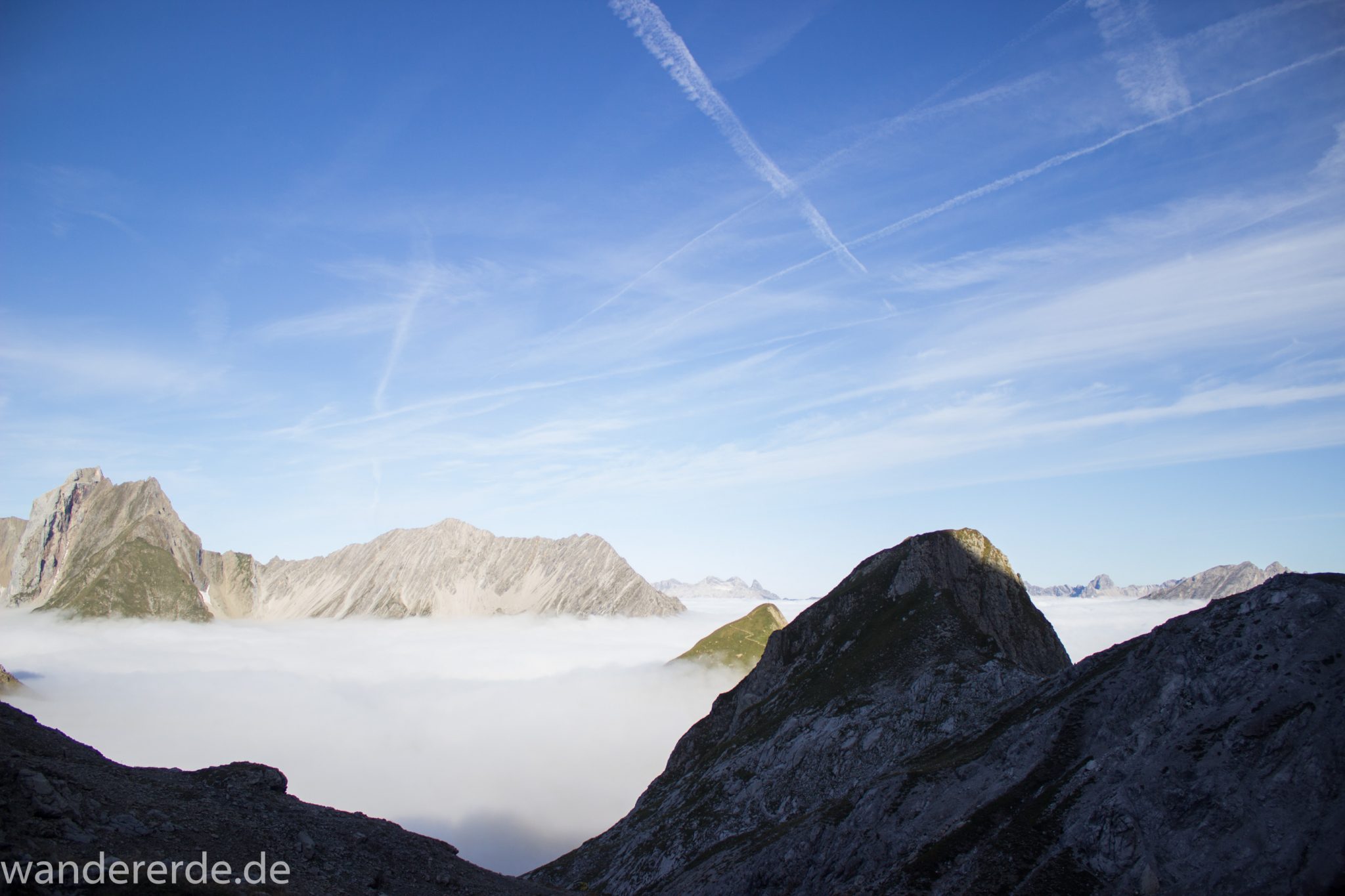 Alpenüberquerung Fernwanderweg E5 Oberstdorf Meran, 3. Etappe von Memminger Hütte zur Skihütte Zams, Berge sind am frühen Morgen noch in Nebel getaucht, aber die Sonne scheint, herrliches Wetter zum Wandern, E5 Wanderweg führt zu Beginn der dritten Etappe ab der Memminger Hütte über steilen und ausgesetzten Wanderweg über die Seescharte, ringsum Aussicht auf Berge der Alpen