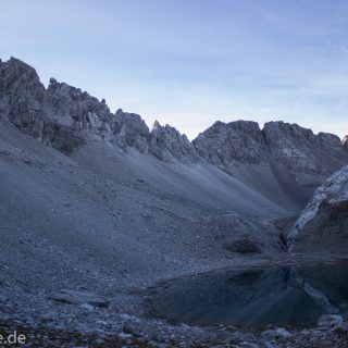 Alpenüberquerung Fernwanderweg E5 Oberstdorf Meran, 3. Etappe von Memminger Hütte zur Skihütte Zams, E5 Wanderweg führt zu Beginn der dritten Etappe ab der Memminger Hütte über steilen und ausgesetzten Wanderweg über die Seescharte, Blick auf kristallklaren Bergsee während Aufstieg zur Seescharte auf sehr schmalen Wanderweg über viel Geröll, Aussicht auf Berge der Alpen