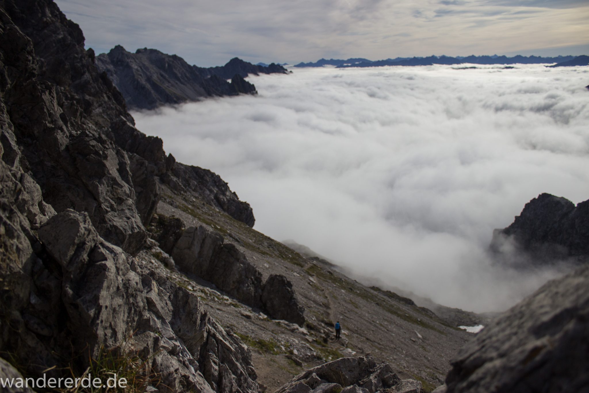 Alpenüberquerung Fernwanderweg E5 Oberstdorf Meran, 3. Etappe von Memminger Hütte zur Skihütte Zams, E5 Wanderweg führt zu Beginn der dritten Etappe ab der Memminger Hütte über steilen und ausgesetzten Wanderweg über die Seescharte, Blick auf die vor einem liegenden Berge der Alpen bei Erreichen der Seescharte, nach langem, steilen Aufstieg auf der schattigen Seite erreicht man damit die sonnige Seite und somit den Beginn eines lange währenden Abstiegs, Blick auf Wanderer der von der Seescharte absteigt Richtung Zams ins Lochbachtal