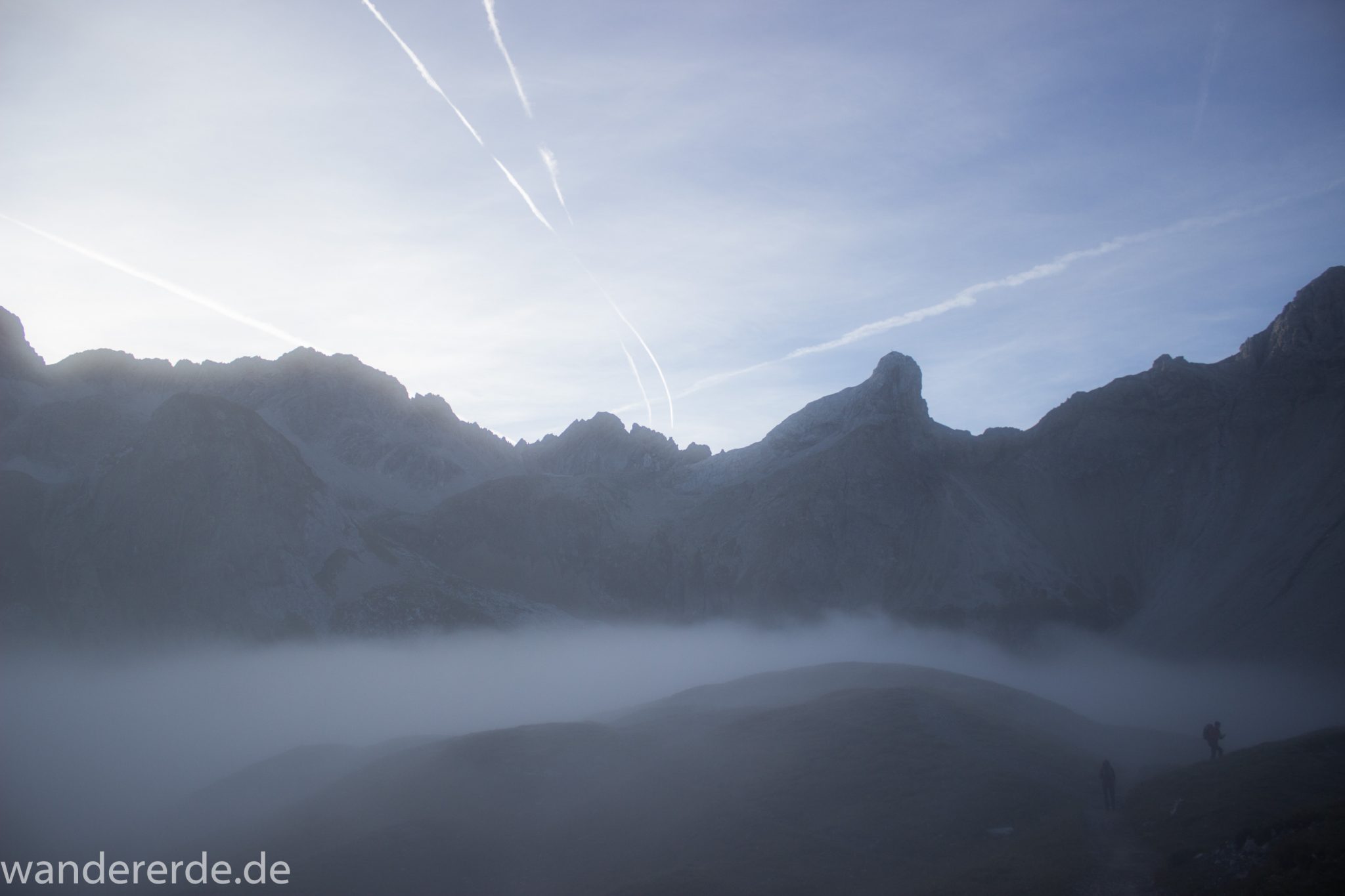 Alpenüberquerung Fernwanderweg E5 Oberstdorf Meran, 3. Etappe von Memminger Hütte zur Skihütte Zams, Berge sind am frühen Morgen noch in Nebel getaucht, aber die Sonne scheint, herrliches Wetter zum Wandern, E5 Wanderweg führt zu Beginn der dritten Etappe ab der Memminger Hütte über steilen und ausgesetzten Wanderweg über die Seescharte, Blick auf Wanderer im Nebel