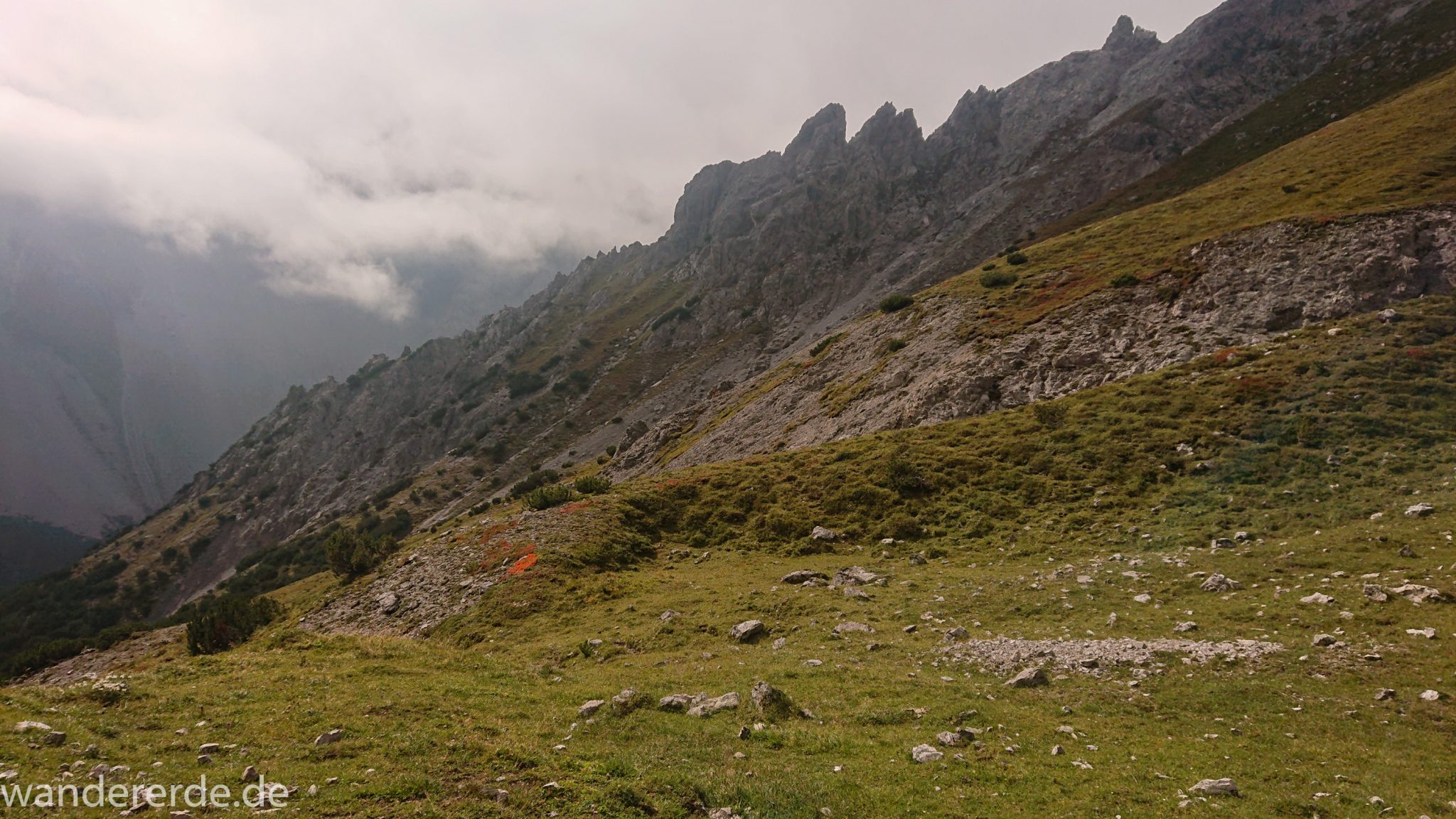 Alpenüberquerung Fernwanderweg E5 Oberstdorf Meran, 3. Etappe von Memminger Hütte zur Skihütte Zams, nach Erreichen der Seescharte folgt ein sehr langer Abstieg ins Lochbachtal Richtung Zams, Aussicht auf Berggipfel und Bergwiesen, Berge und Umgebung liegen teils im Nebel verborgen